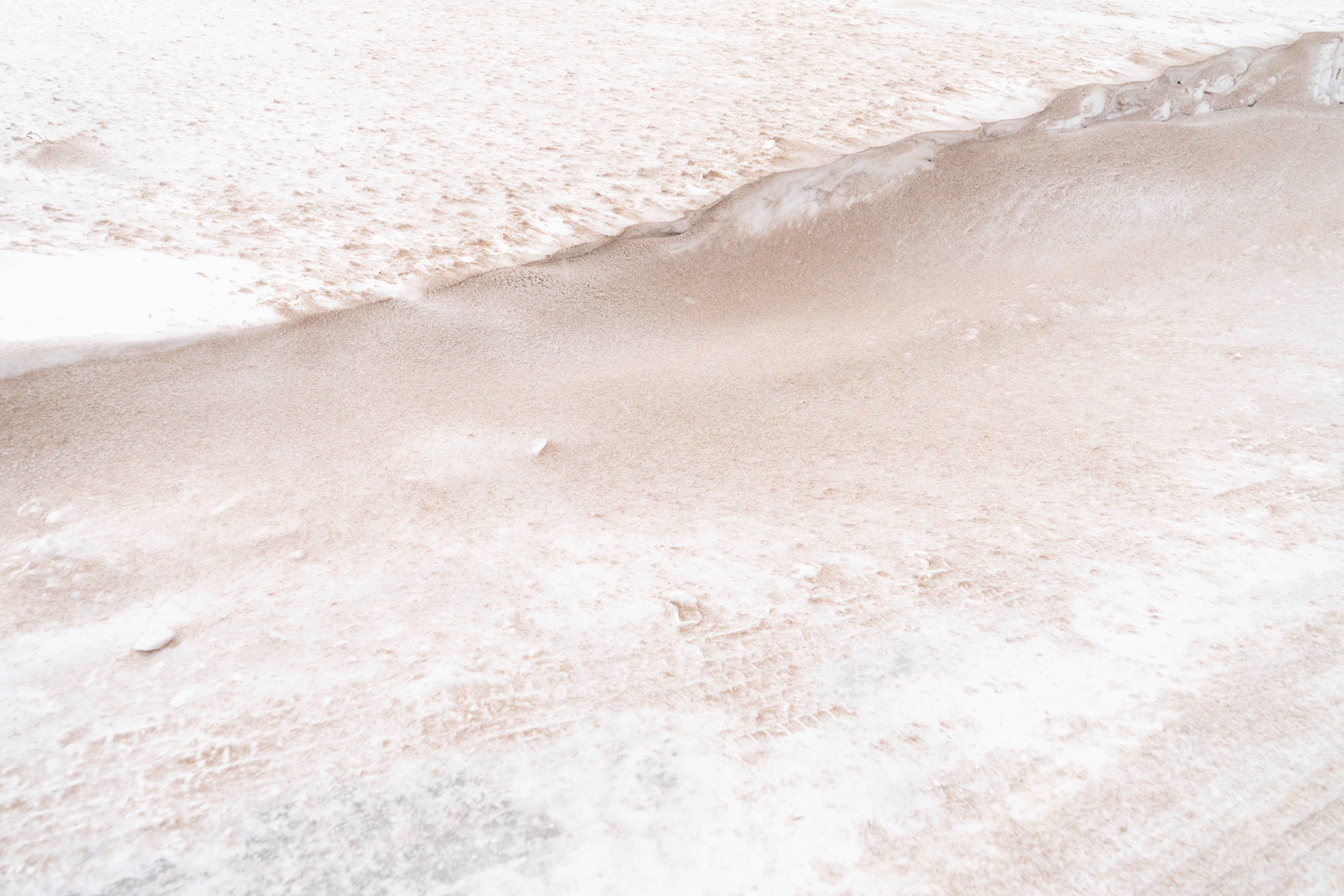 Beige Minimalist 桌布 壁紙 — 冬季景觀中帶有柔和起伏和細微腳印的質感雪地特寫。
