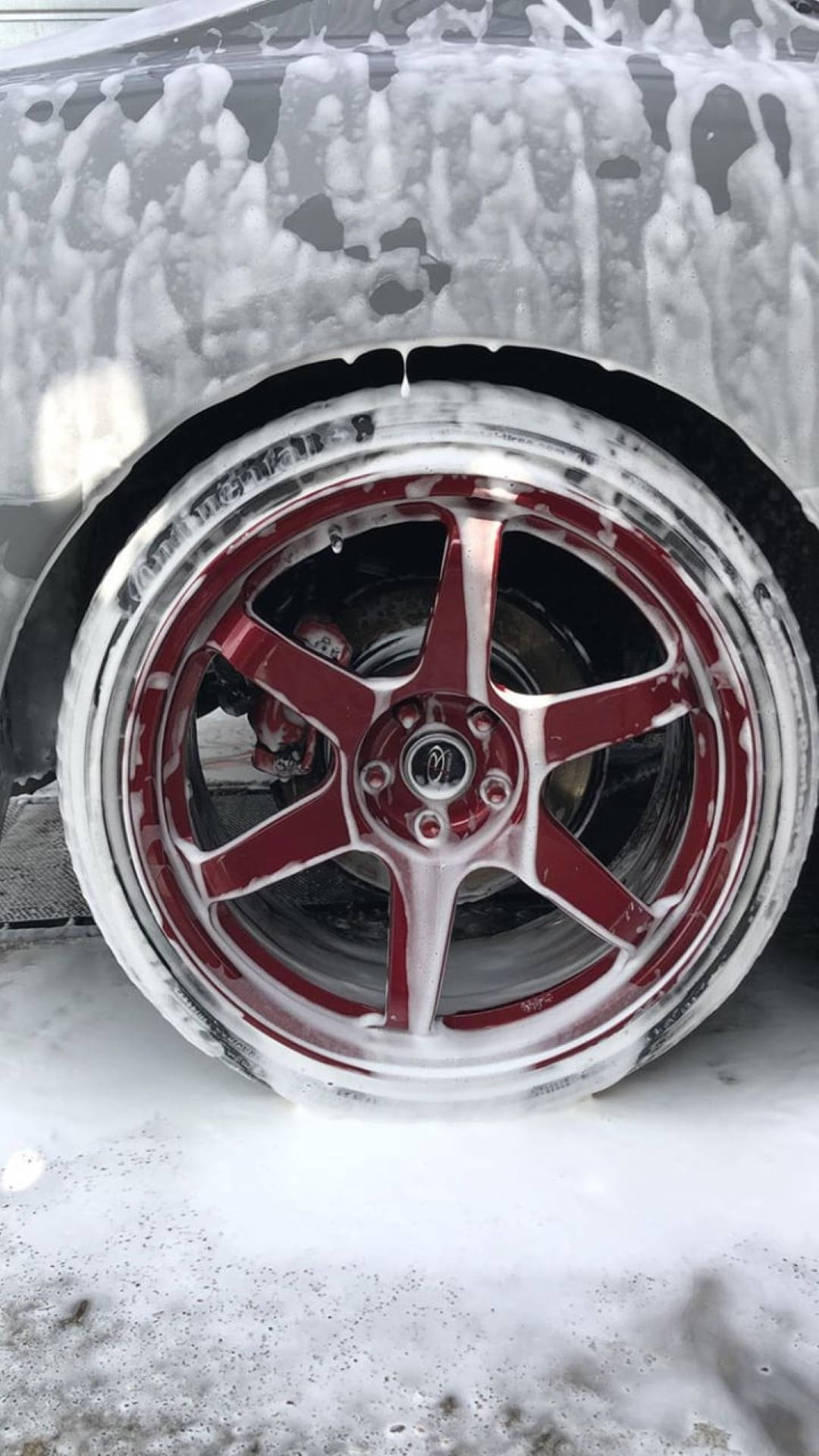 Wash 桌布 壁紙 — 冬季洗車期間，車上紅色和銀色合金輪圈的特寫，覆蓋著白色肥皂泡。