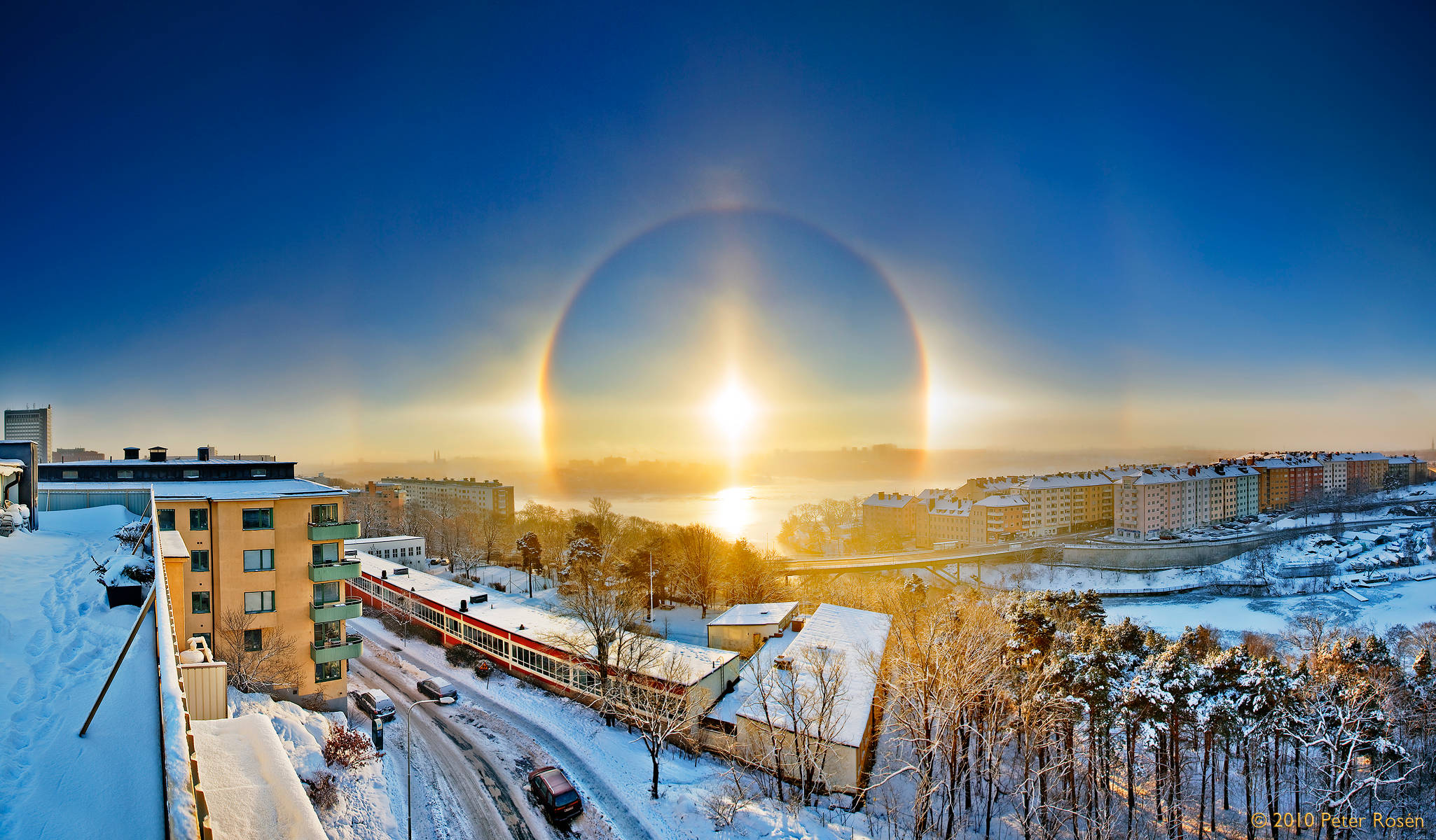 Sweden 桌布 壁紙 — 冬日雪景城市上空壯麗的日出，一道鮮明的太陽光暈拱繞著耀眼的太陽。