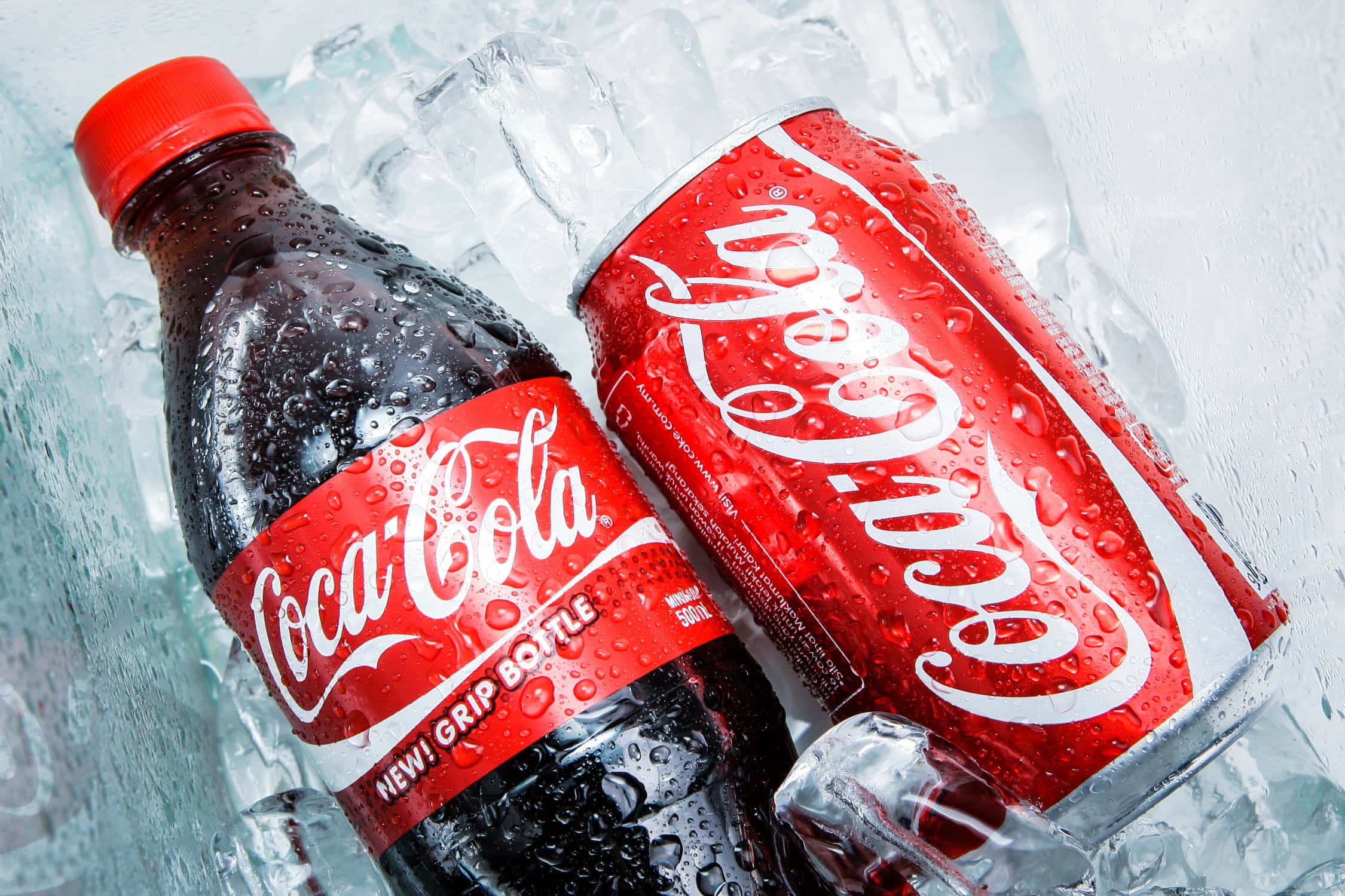 coca cola 桌布 壁紙 — 冰凍可口可樂瓶及罐，置於閃爍冰塊中，帶有冷凝水滴。