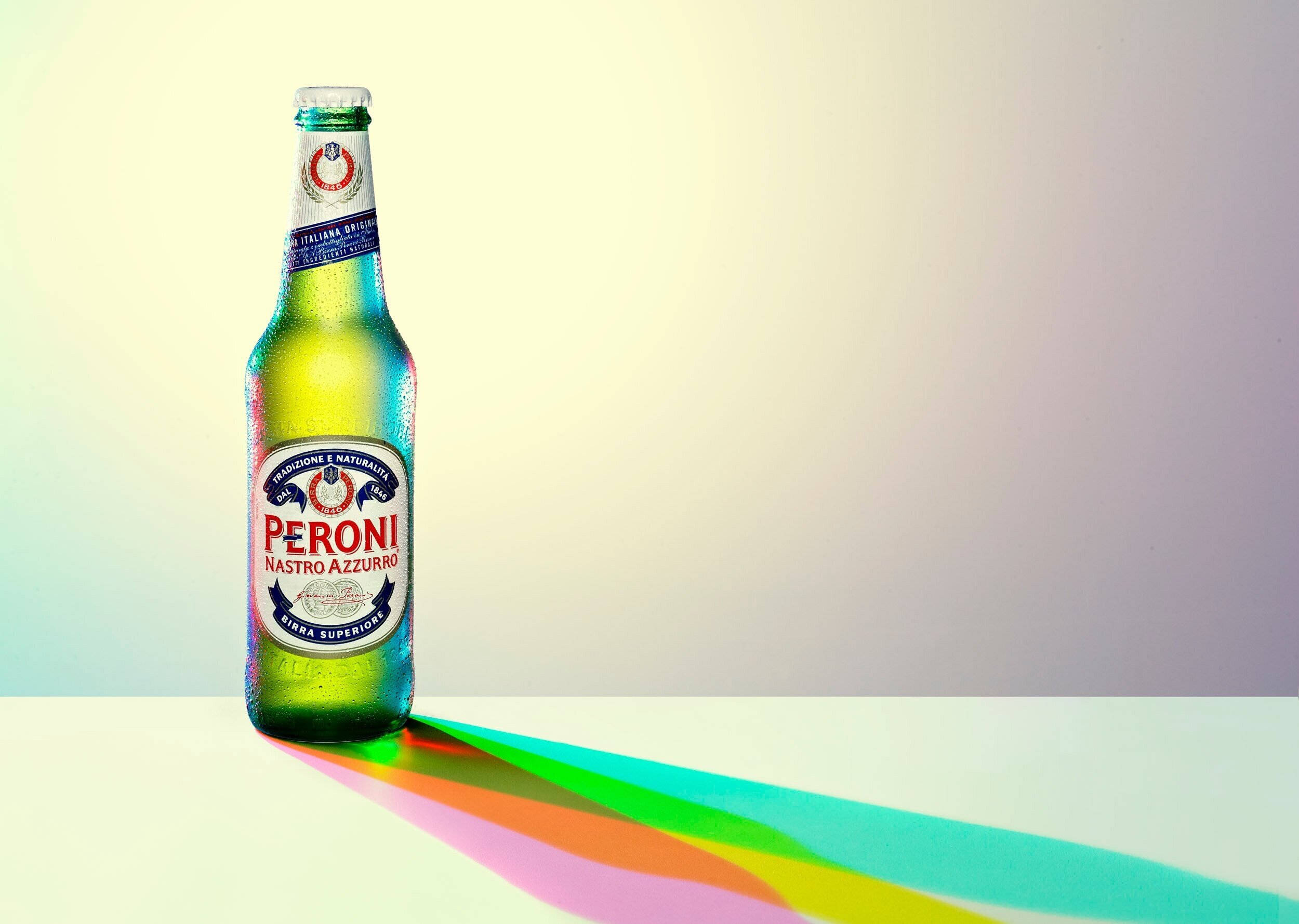 Light 桌布 壁紙 — 冰凍的Peroni Nastro Azzurro啤酒瓶在簡約的白色表面上投射出鮮豔的彩虹陰影，背景為柔和的漸變色。
