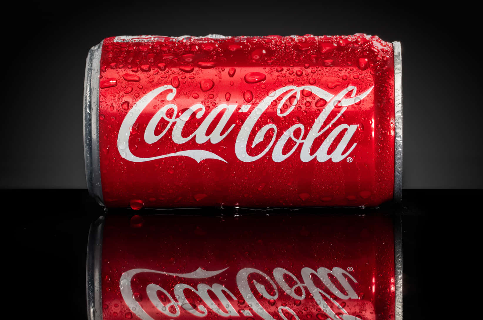 coca cola 桌布 壁紙 — 冰凍的可口可樂罐在深色反光表面上閃爍著冷凝水珠。
