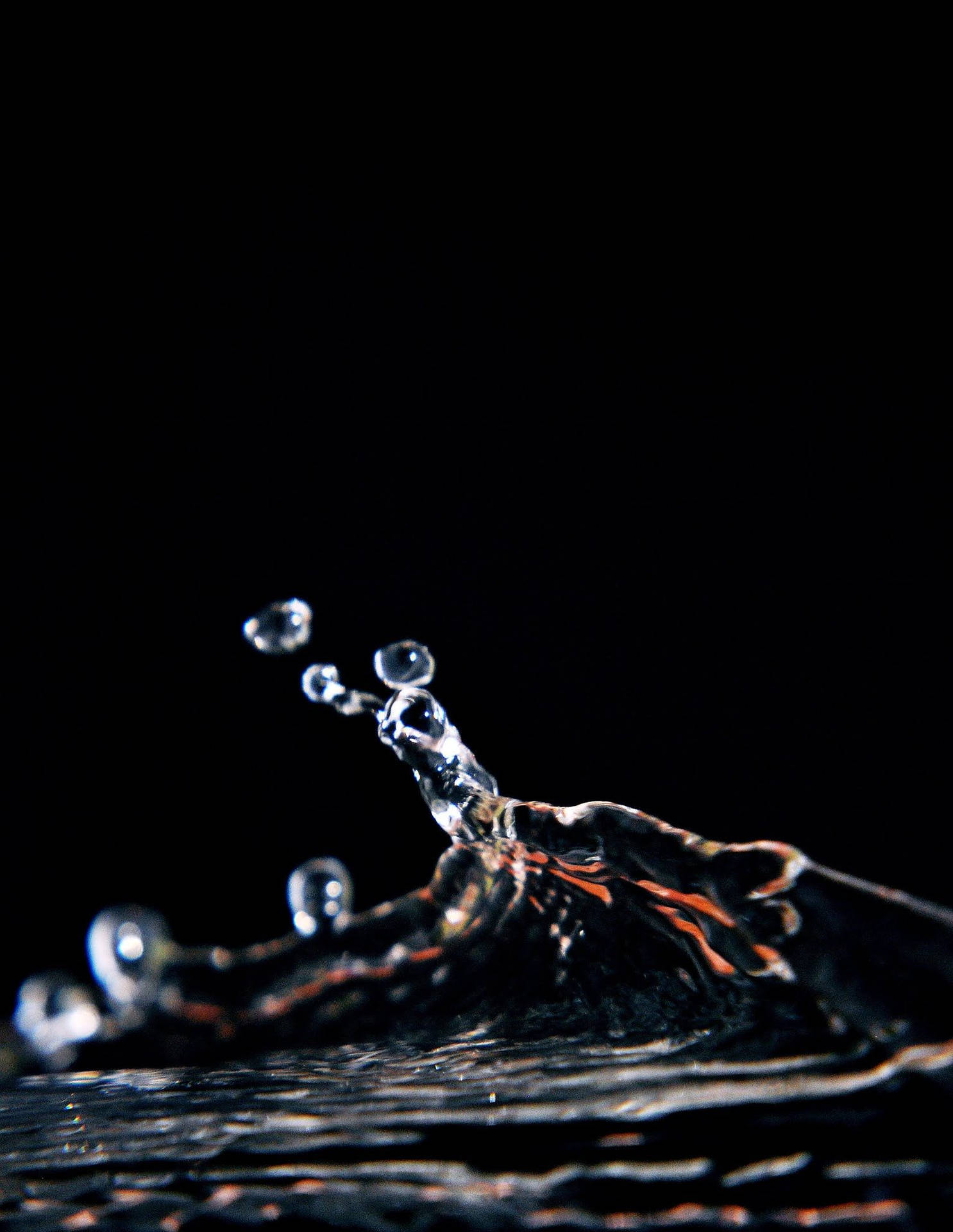 Water 桌布 壁紙 — 冰凍的水滴飛濺形成弧線，襯托著純黑背景，帶有微妙的橙色反射。