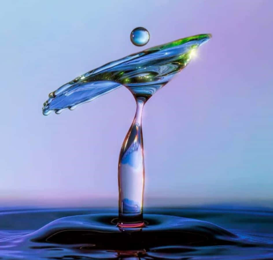 Water Drop 桌布 壁紙 — 冰凍的水花形成完美的皇冠，一滴水珠懸浮在上方，背景是柔和的紫藍色漸變天空。