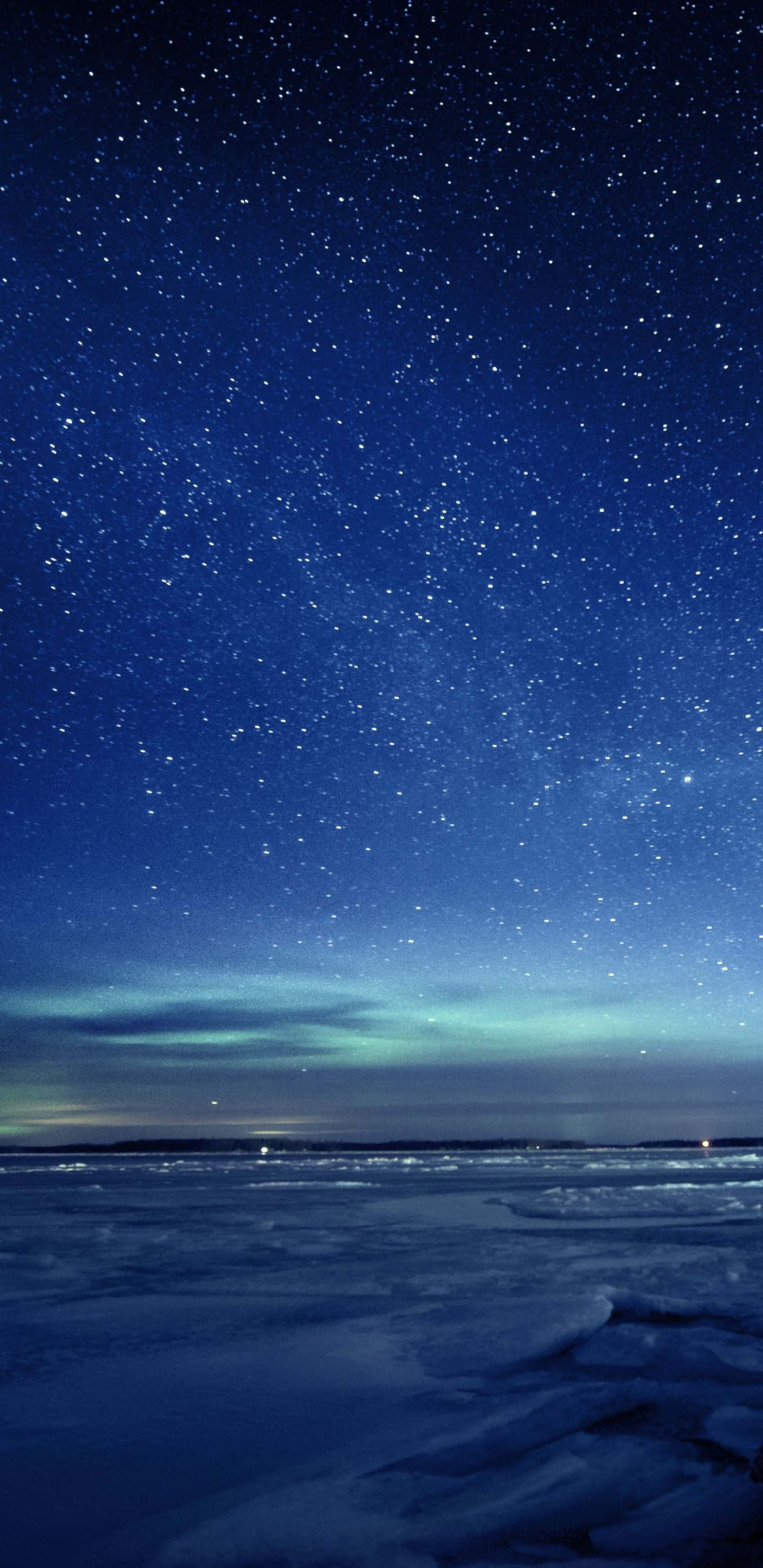 Starry Night Sky 桌布 壁紙 — 冰凍的湖面，星空下，地平線上有微弱的綠色極光閃爍。