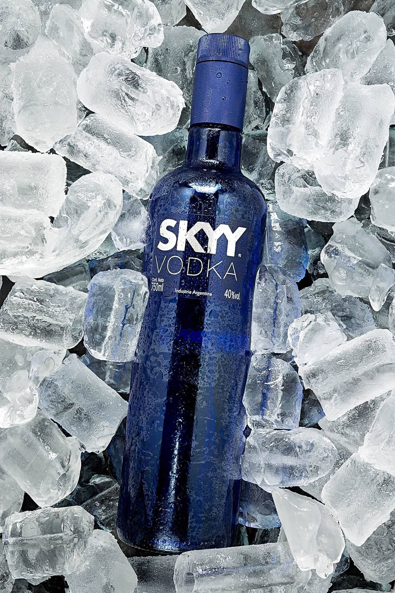 Drink 桌布 壁紙 — 冰凍的藍色Skyy伏特加酒瓶，置於閃爍的冰塊中，帶有冷凝水滴。