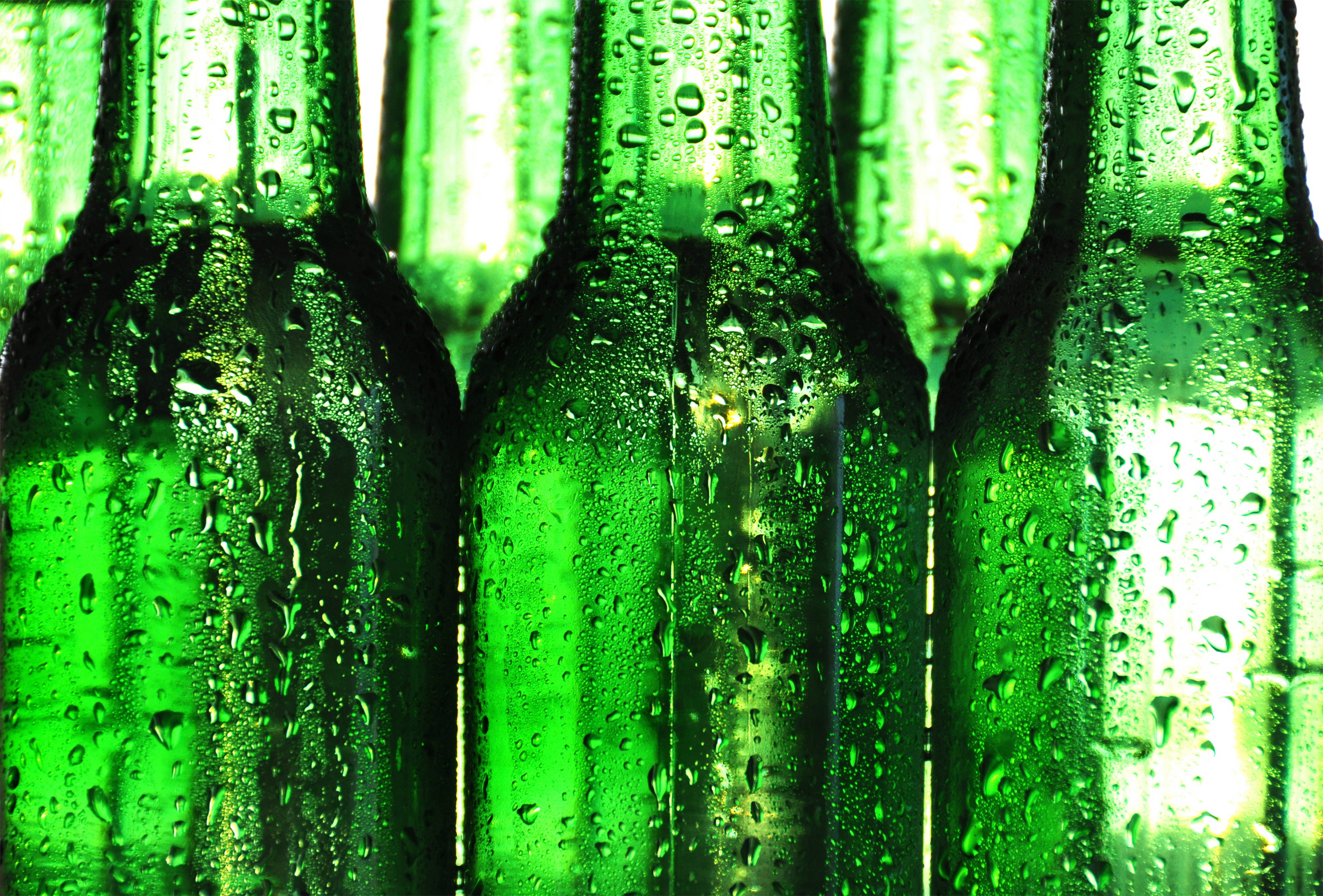Beer 桌布 壁紙 — 冰凍綠色玻璃瓶的特寫，瓶身佈滿冷凝水滴，在明亮的背光下閃閃發光。