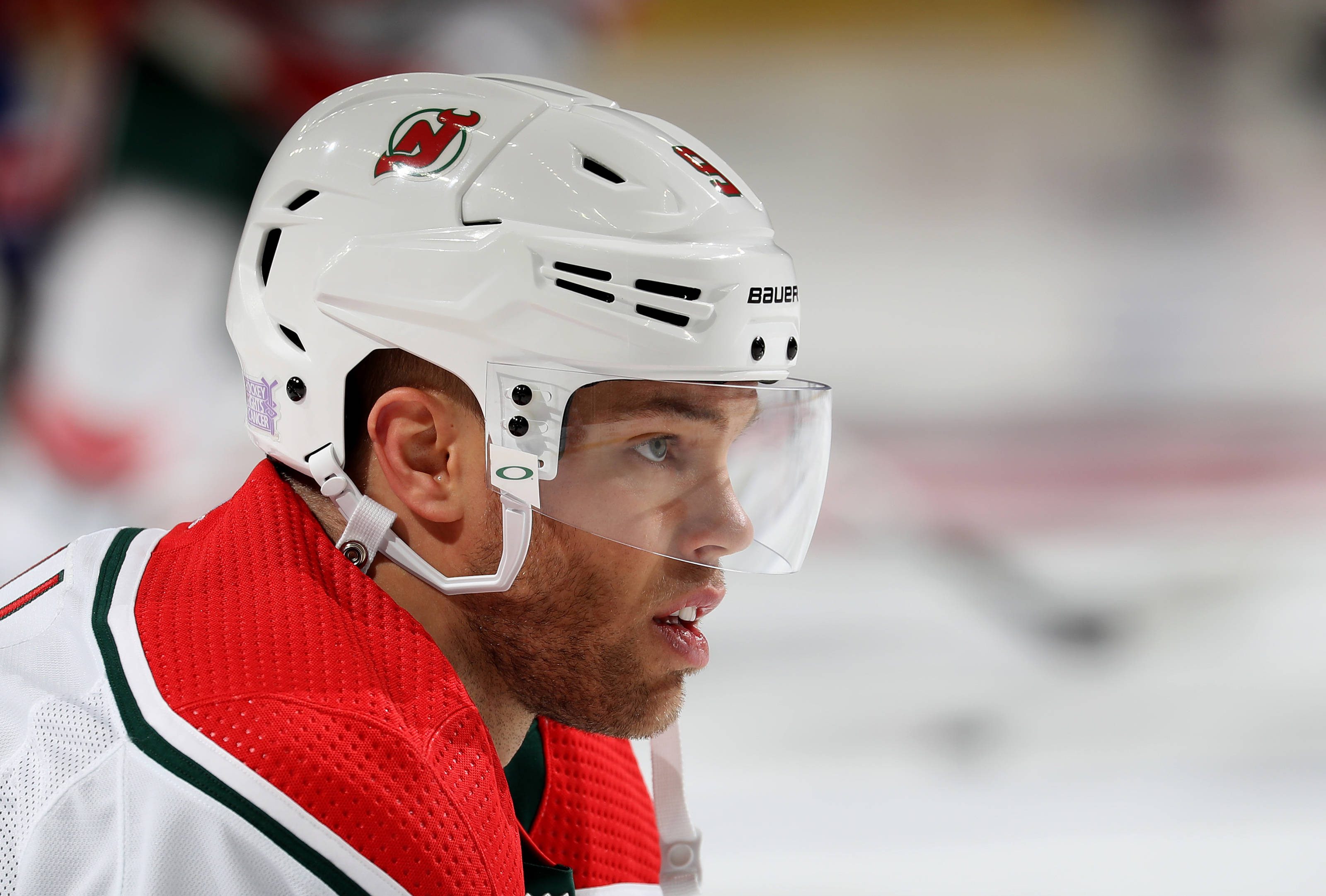 hockey 桌布 壁紙 — 冰場上專注的曲棍球運動員近距離特寫，戴白色頭盔，穿紅色球衣。