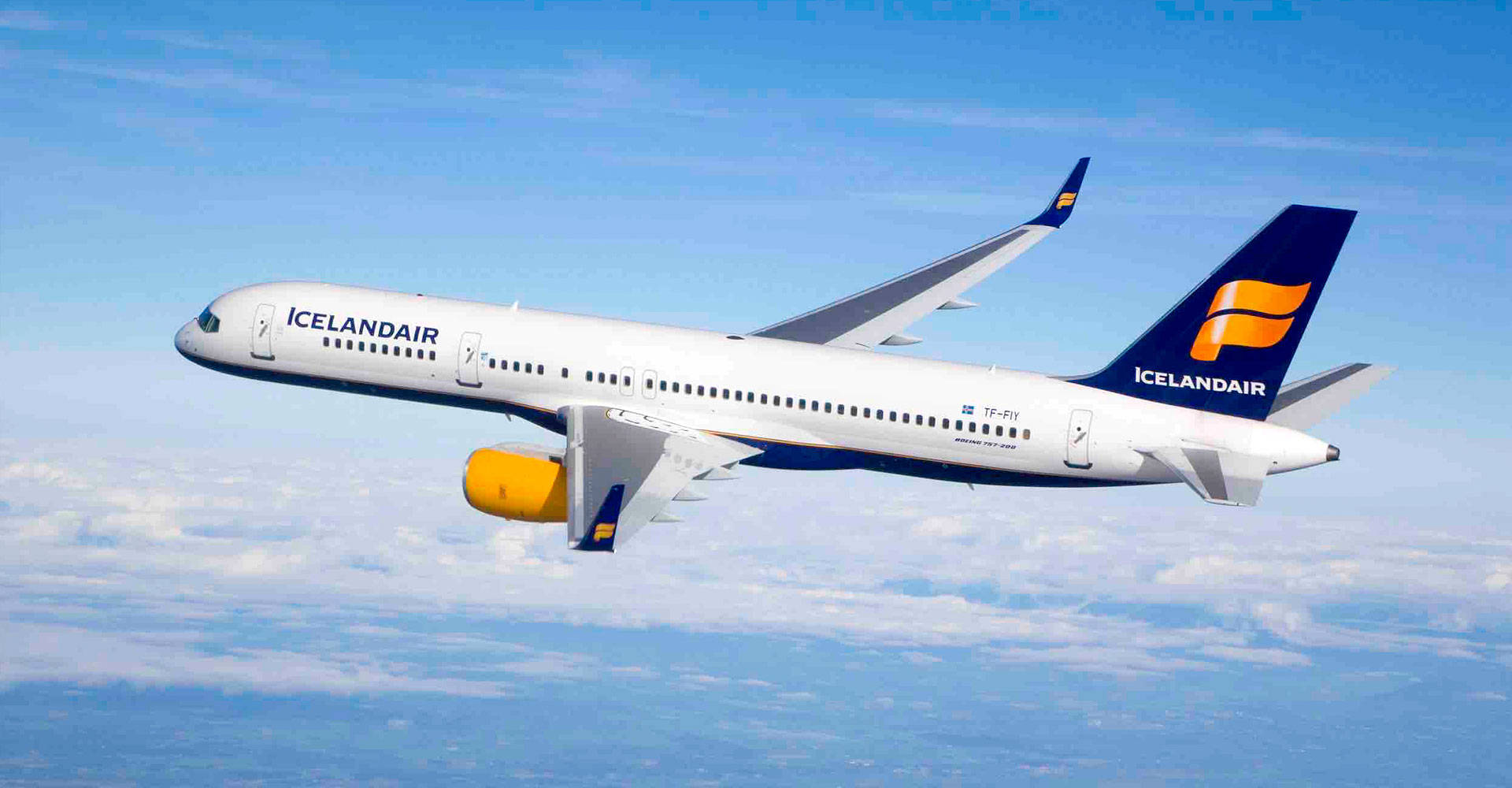 flying 桌布 壁紙 — 冰島航空飛機在晴朗藍天下翱翔於蓬鬆白雲之上，引擎帶有鮮豔黃色點綴。