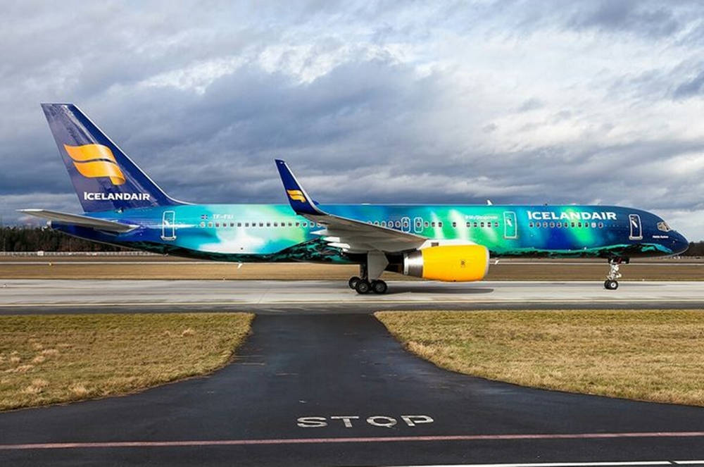 Aviation 桌布 壁紙 — 冰島航空飛機帶有極光塗裝，在多雲天空下滑行在跑道上。