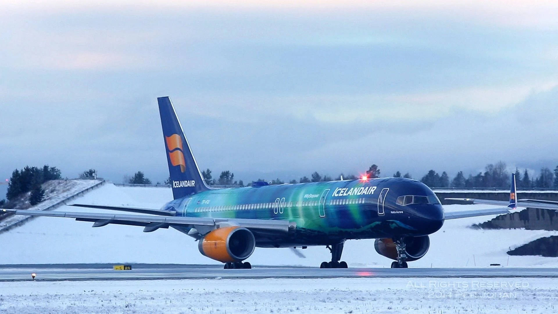 飛機 桌布 壁紙 — 冰島航空飛機帶有極光靈感塗裝，在陰天下滑行於積雪跑道。