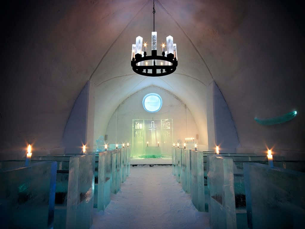 Ice Hotel 桌布 壁紙 — 冰教堂內部，拱形天花板下，燭光與吊燈照亮半透明藍色長椅。