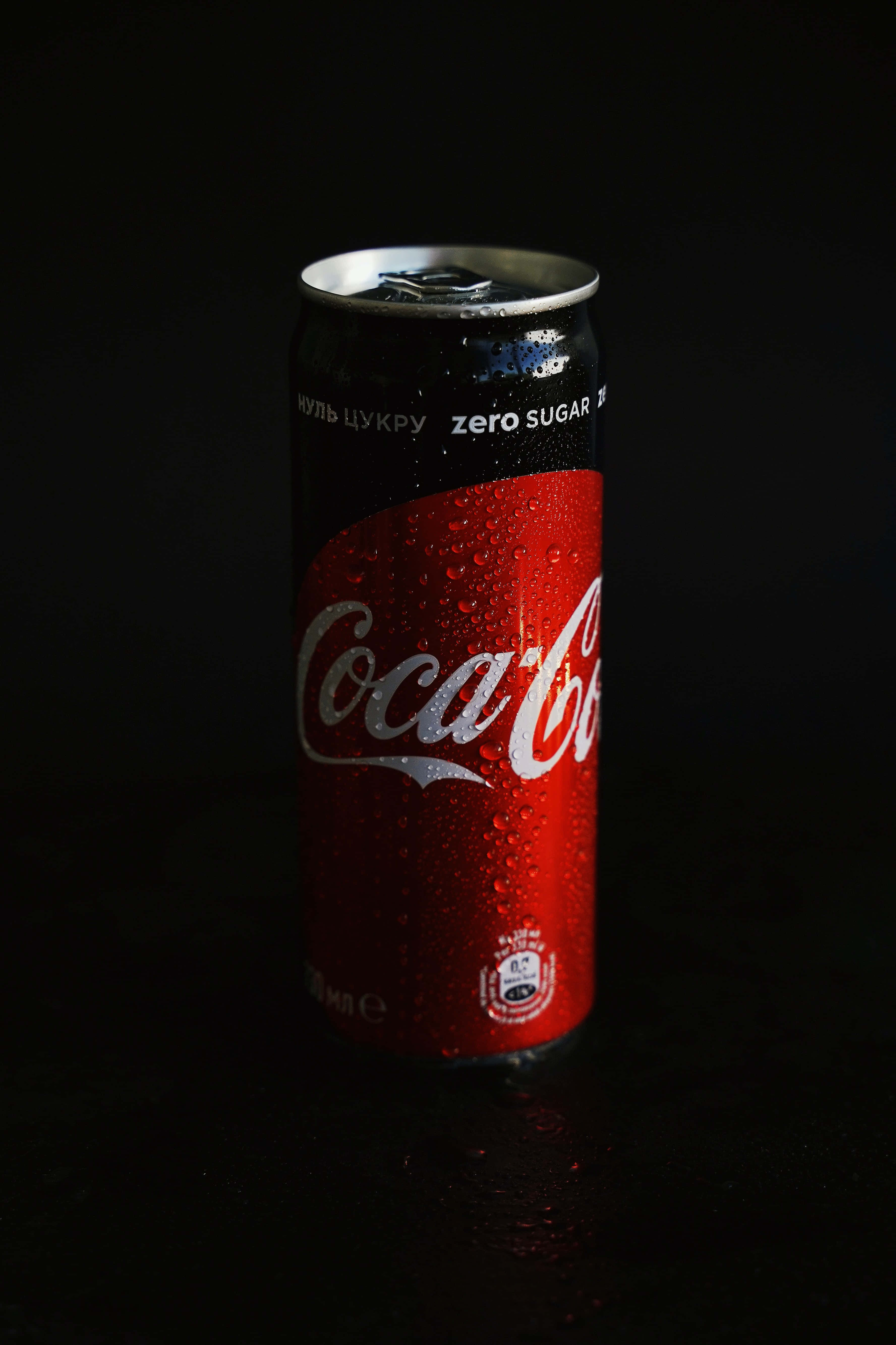 coca cola 桌布 壁紙 — 冰涼的Coca-Cola Zero Sugar罐在純黑背景上閃爍著冷凝水珠。