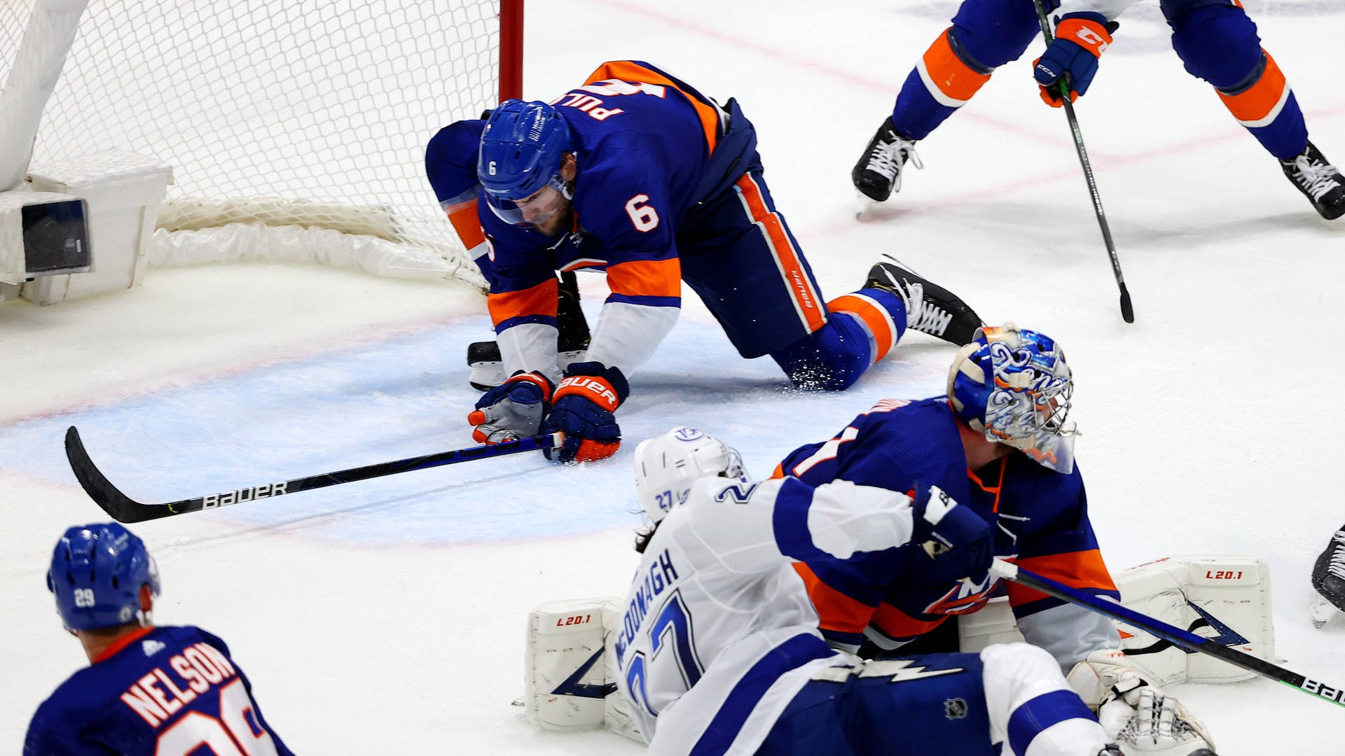 New 桌布 壁紙 — 冰球守門員身穿藍色和橙色裝備，飛身撲救阻擋射門，而對方球員正滑向球門。