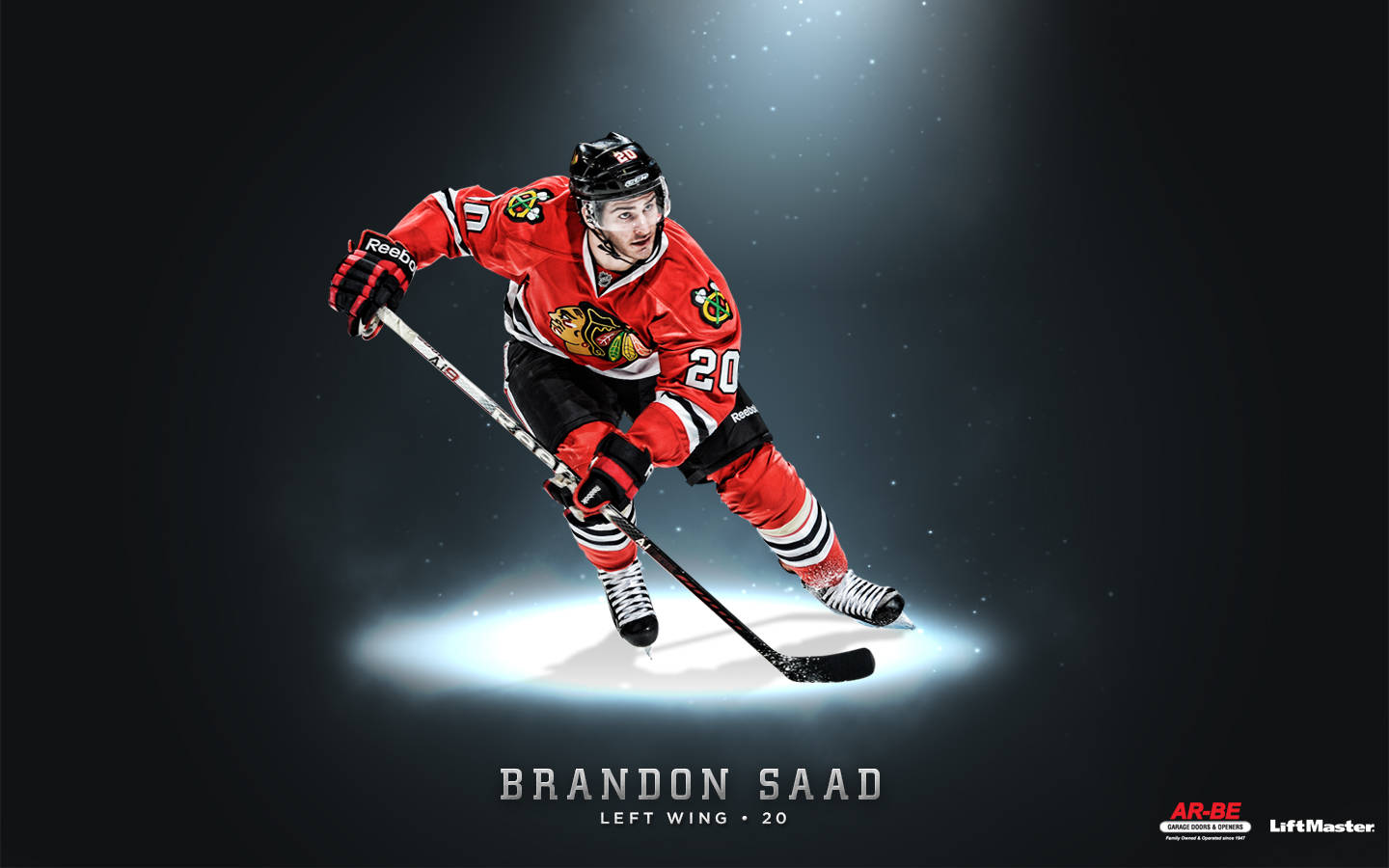 Blackhawks 桌布 壁紙 — 冰球運動員 Brandon Saad 穿著紅色 Blackhawks 裝備，在黑暗冰場的聚光燈下動態滑行。