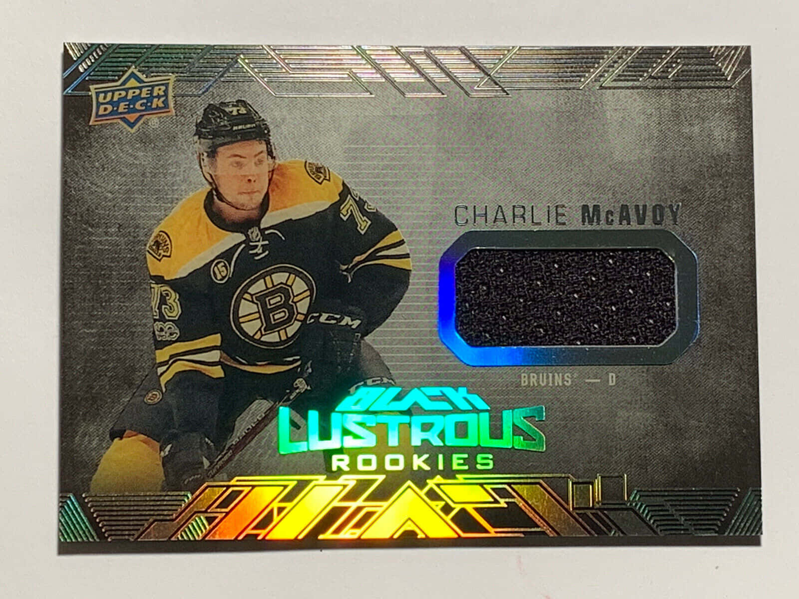 運動 桌布 壁紙 — 冰球運動員 Charlie McAvoy 身穿棕熊隊裝備，在一張帶有黑色球衣補丁和螢光綠色全息文字的閃亮交易卡上擺姿勢。