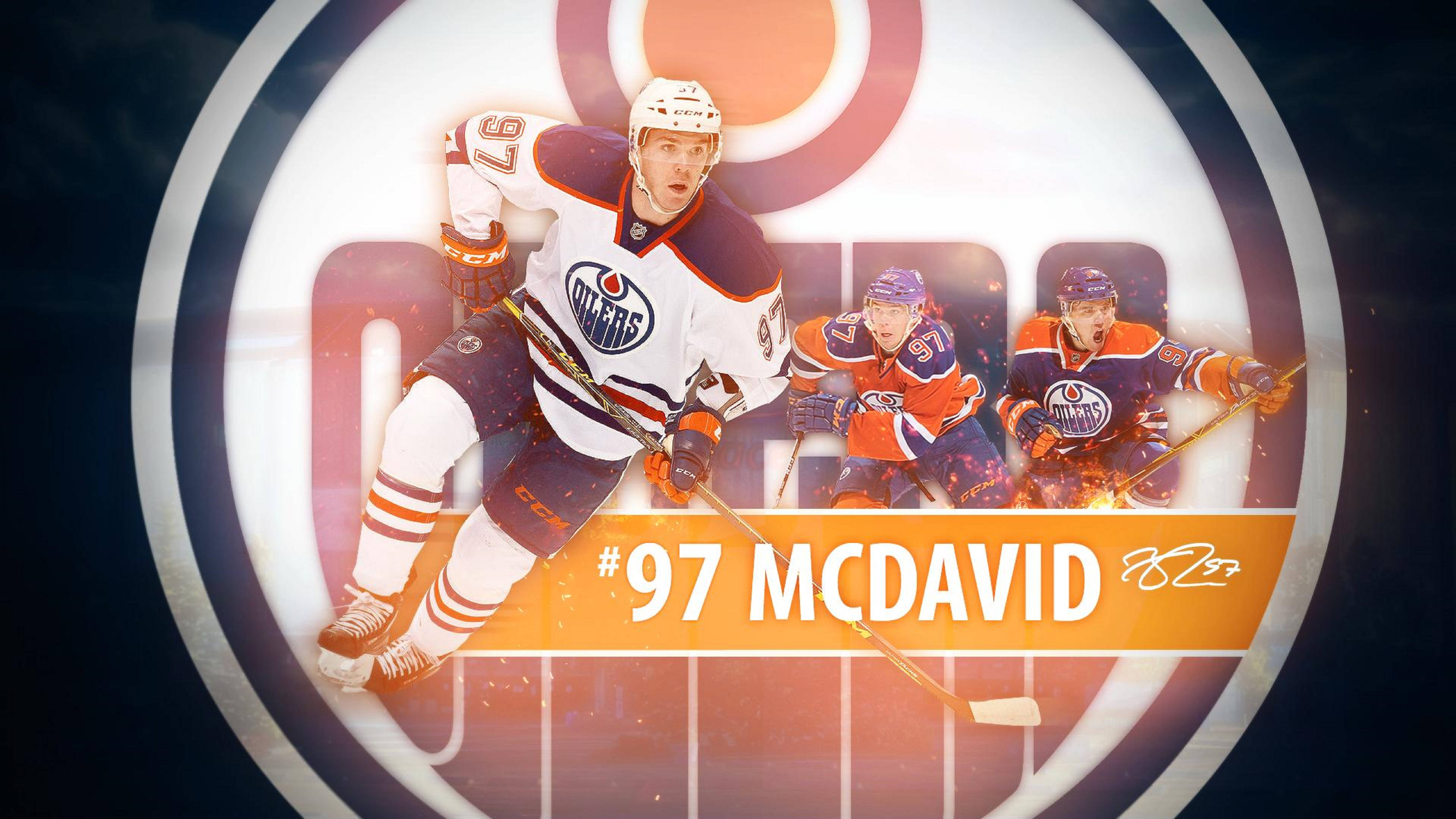 Oilers 桌布 壁紙 — 冰球運動員 Connor McDavid 身穿白色油人隊球衣，在隊友背景和球隊標誌背景下動態向前滑行。
