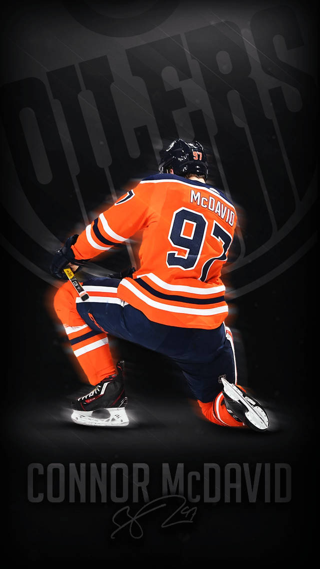hockey 桌布 壁紙 — 冰球運動員 Connor McDavid 身穿橙色 97 號球衣，在黑暗背景下動態蹲下，冰鞋閃閃發光。