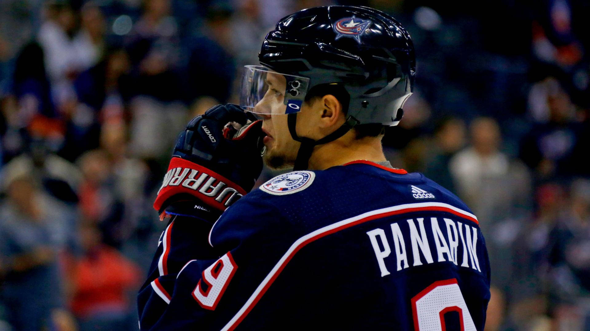 運動 桌布 壁紙 — 冰球運動員 Panarin 身穿深藍色球衣（9號），戴著頭盔和手套，在冰場上微微轉頭。