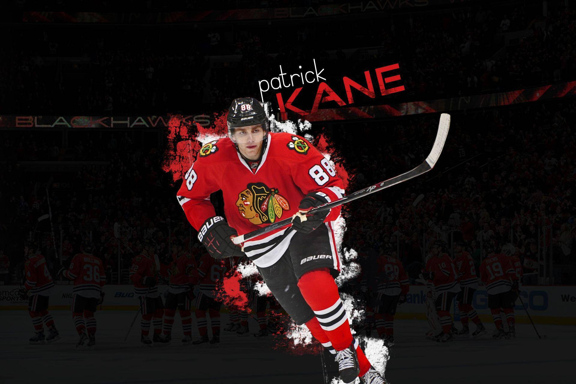 運動 桌布 壁紙 — 冰球運動員 Patrick Kane 身穿紅色 Blackhawks 球衣，在黑暗的競技場背景下動態滑冰，手持冰球桿。
