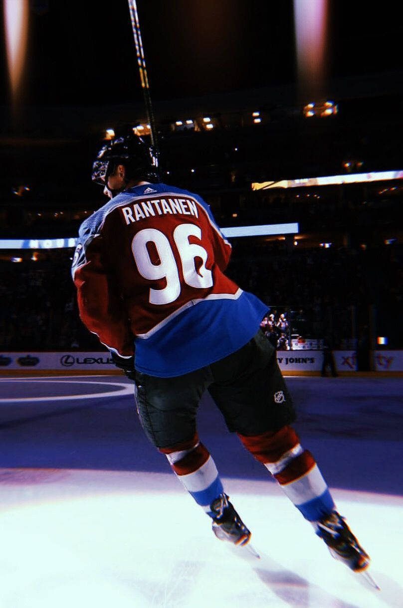 hockey 桌布 壁紙 — 冰球運動員 Rantanen 96 號在場館燈光下動態滑冰，背景是模糊的人群。