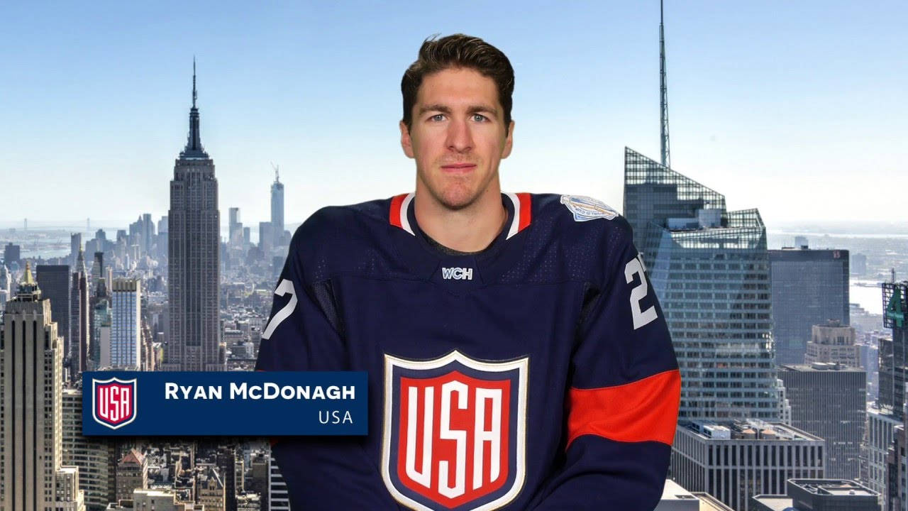運動 桌布 壁紙 — 冰球運動員 Ryan McDonagh 身穿美國隊球衣，自信地站在明亮的藍天下，背後是標誌性的紐約市天際線。