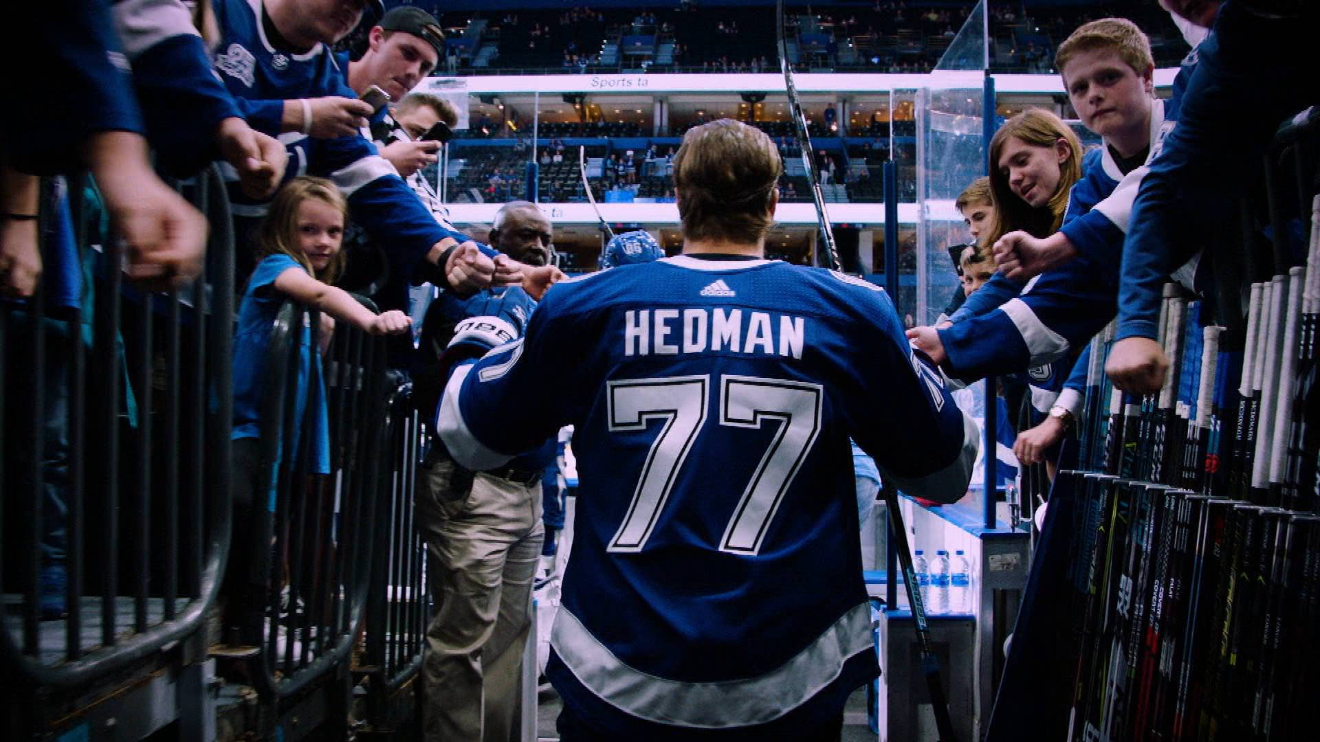 hockey 桌布 壁紙 — 冰球運動員Hedman 77號身穿藍色球衣在溜冰場圍欄旁為粉絲簽名並打招呼。