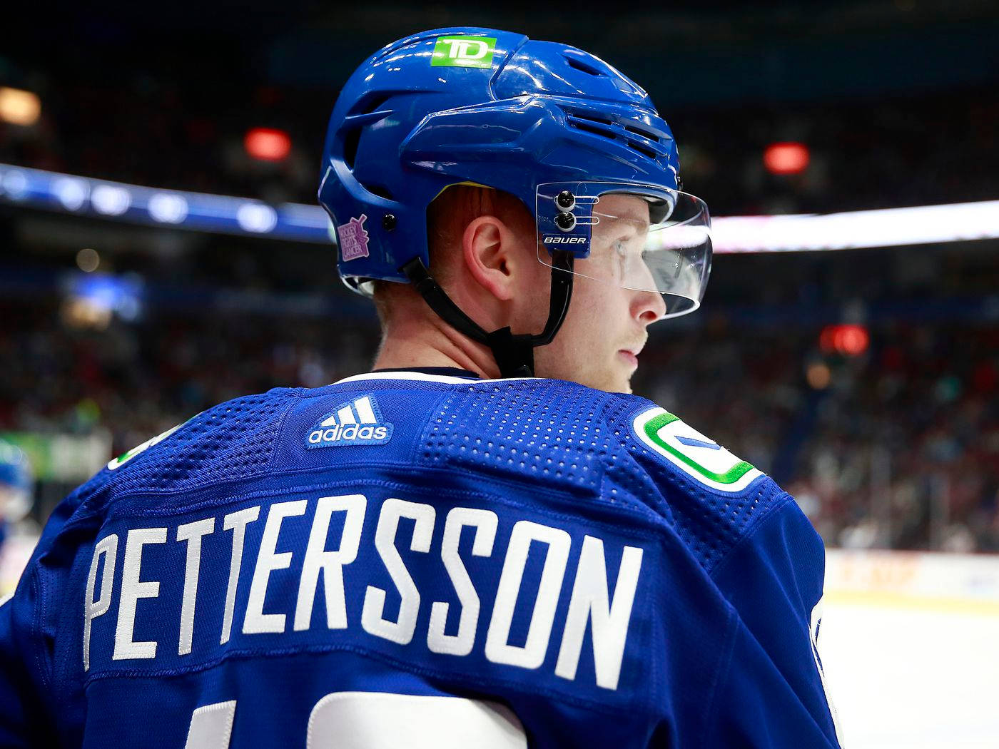 hockey 桌布 壁紙 — 冰球運動員Pettersson身穿藍色球衣和頭盔，在冰場上回頭看的特寫。