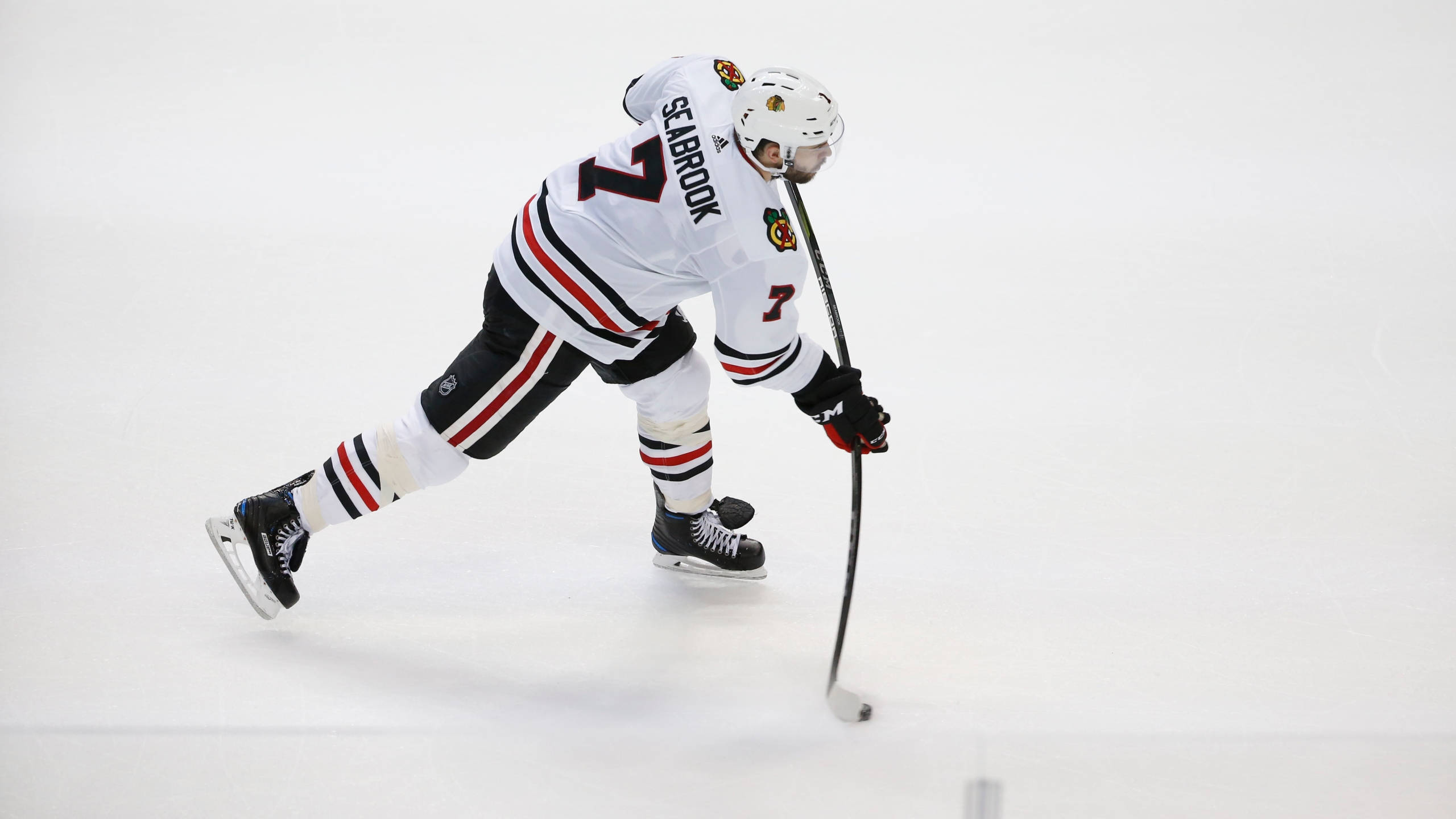 運動 桌布 壁紙 — 冰球運動員Seabrook身穿白色Blackhawks球衣，在比賽中低身俯在冰面上持桿。