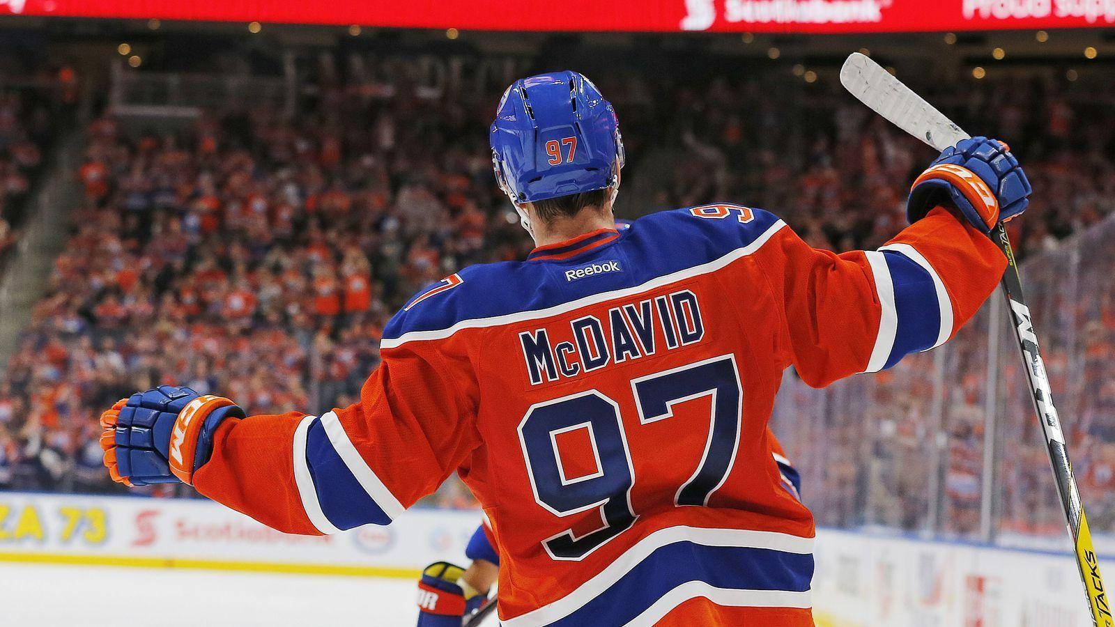 hockey 桌布 壁紙 — 冰球運動員康納·麥克戴維穿著橙色藍色97號球衣，在冰場上高舉雙臂，在歡呼的人群前慶祝。