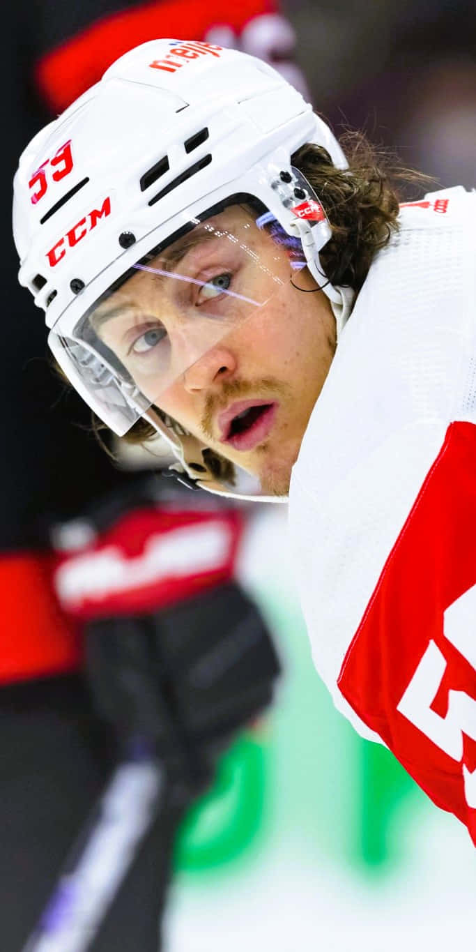 Tyler Bertuzzi 桌布 壁紙 — 冰球運動員的近距離特寫，身穿白色頭盔和帶有紅色點綴的球衣，在比賽中專注地向前看。