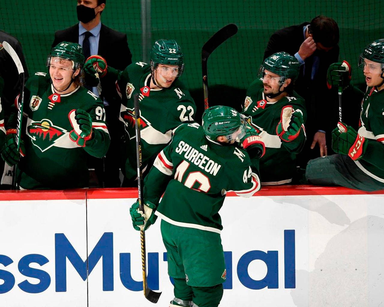 hockey 桌布 壁紙 — 冰球運動員穿著綠色球衣在比賽期間於場邊板牆上熱情慶祝。