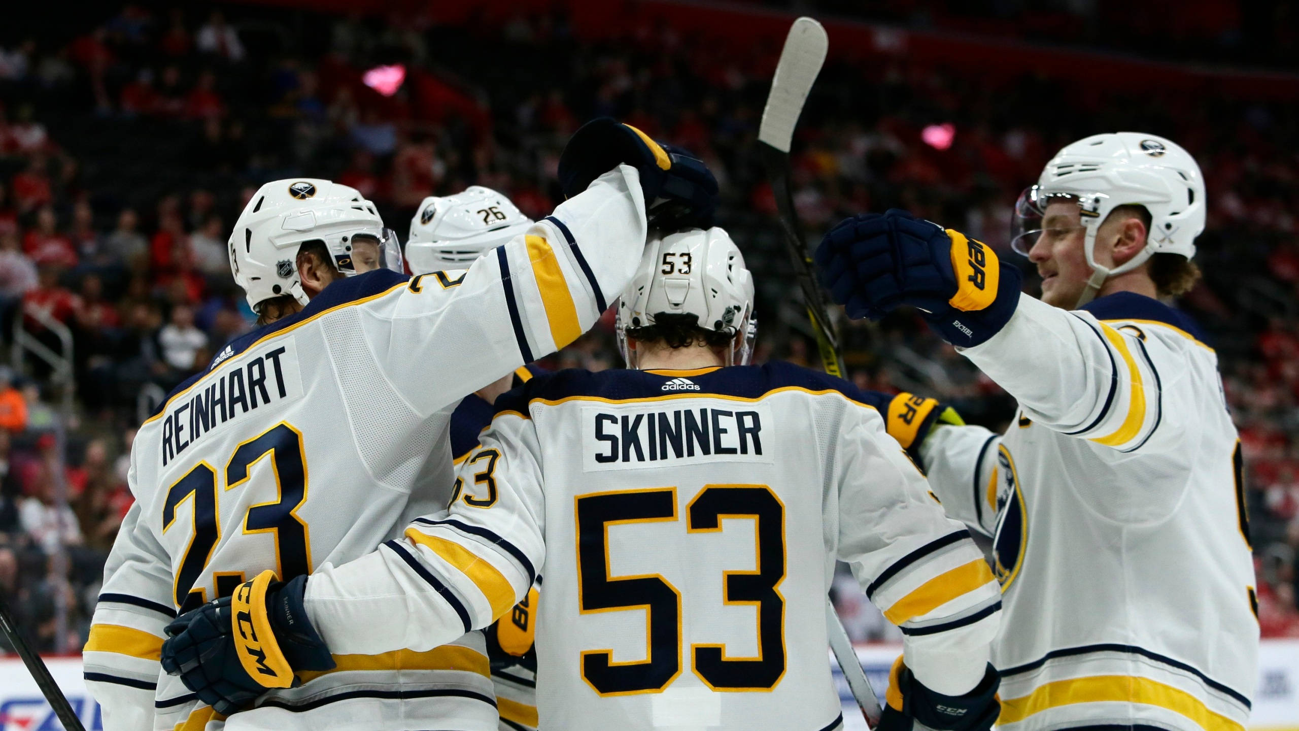 hockey 桌布 壁紙 — 冰球運動員身穿白色和金色球衣，在冰上舉起球棍和頭盔慶祝進球。