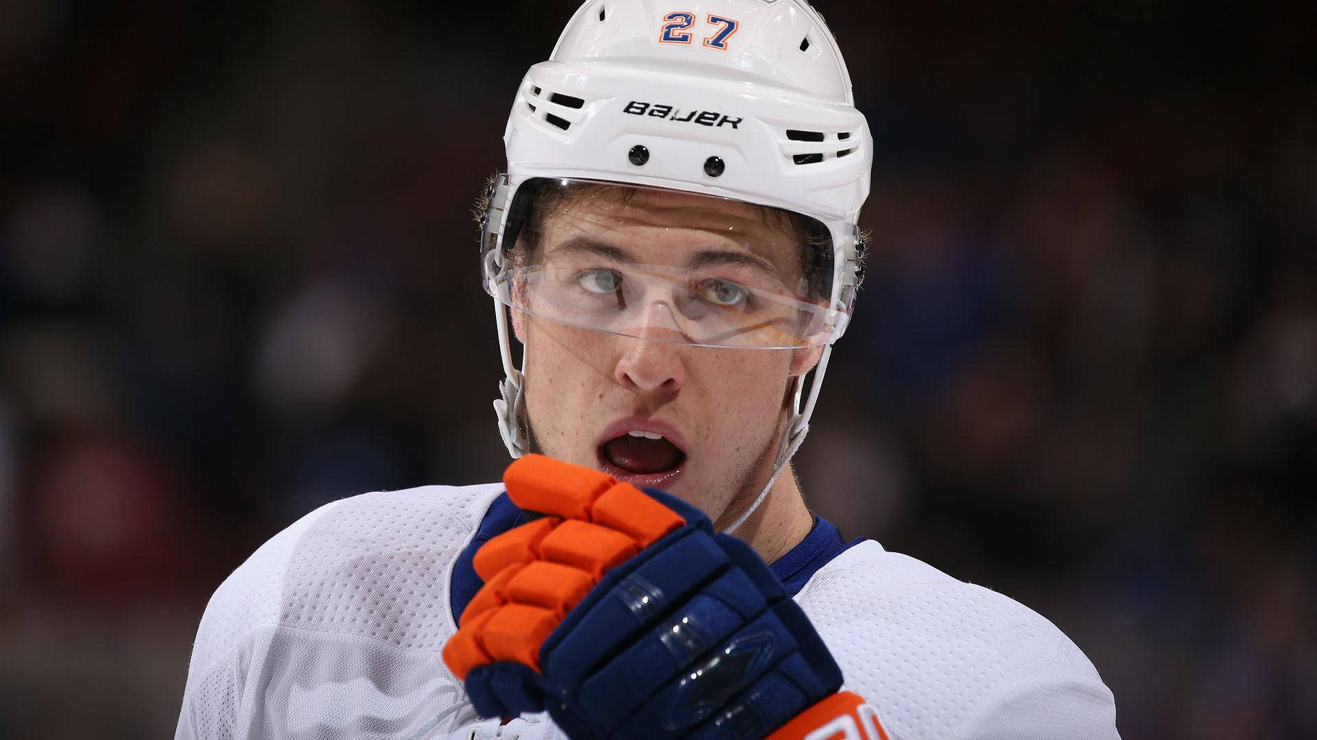 New York Islanders 桌布 壁紙 — 冰球運動員身穿白色裝備和橙色手套，在比賽中專注向上看的特寫。