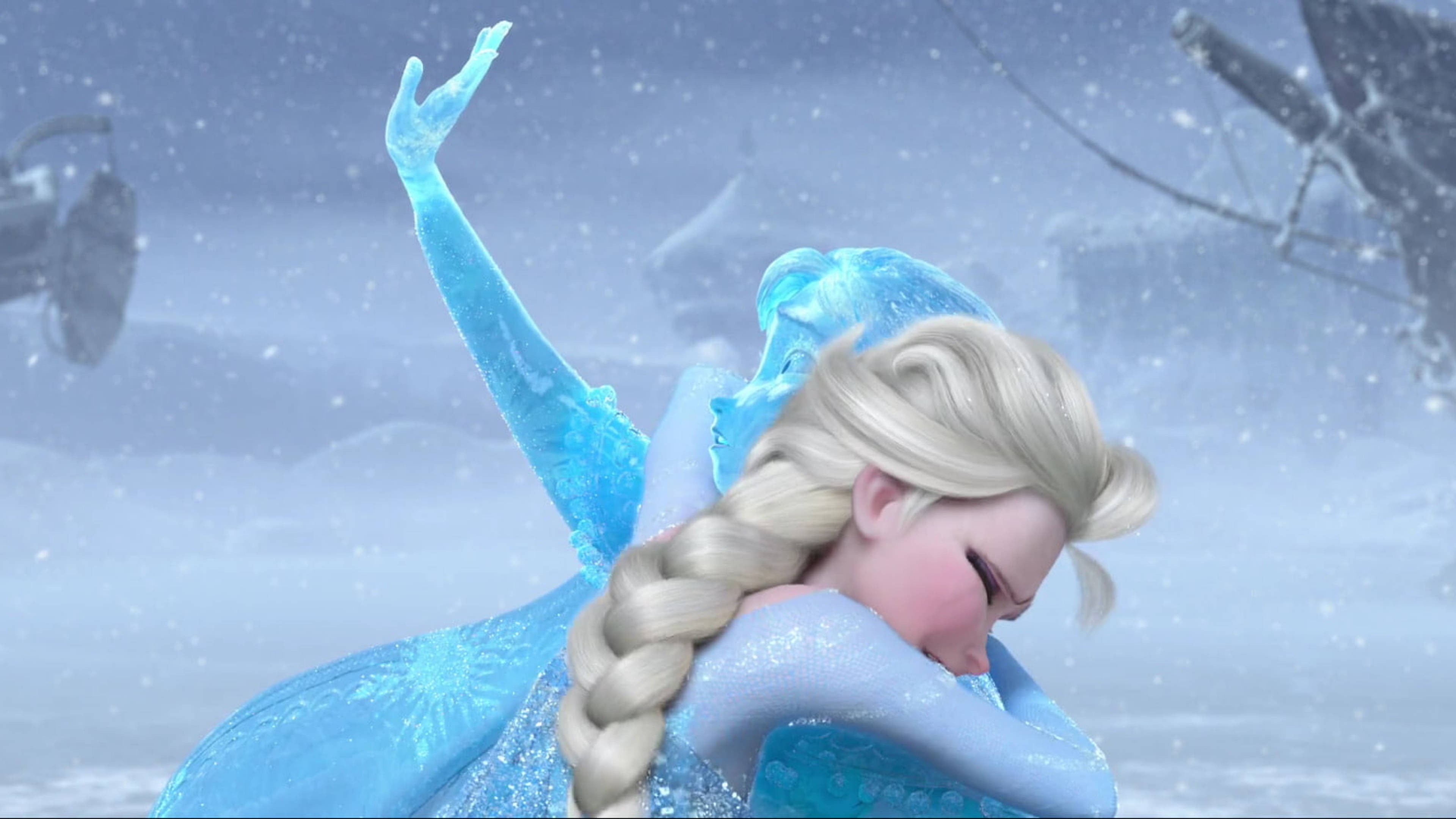 Frozen Elsa 桌布 壁紙 — 《冰雪奇緣》的艾莎站在雪景中，舉起手臂，冰晶在她藍色長裙周圍閃爍。