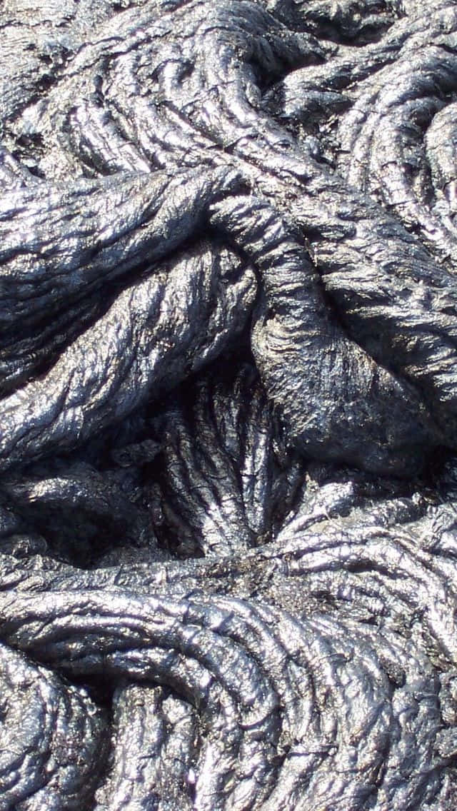 Volcano 桌布 壁紙 — 冷卻熔岩的近距離特寫，在明亮光線下呈現複雜扭曲紋理和金屬銀色亮點。