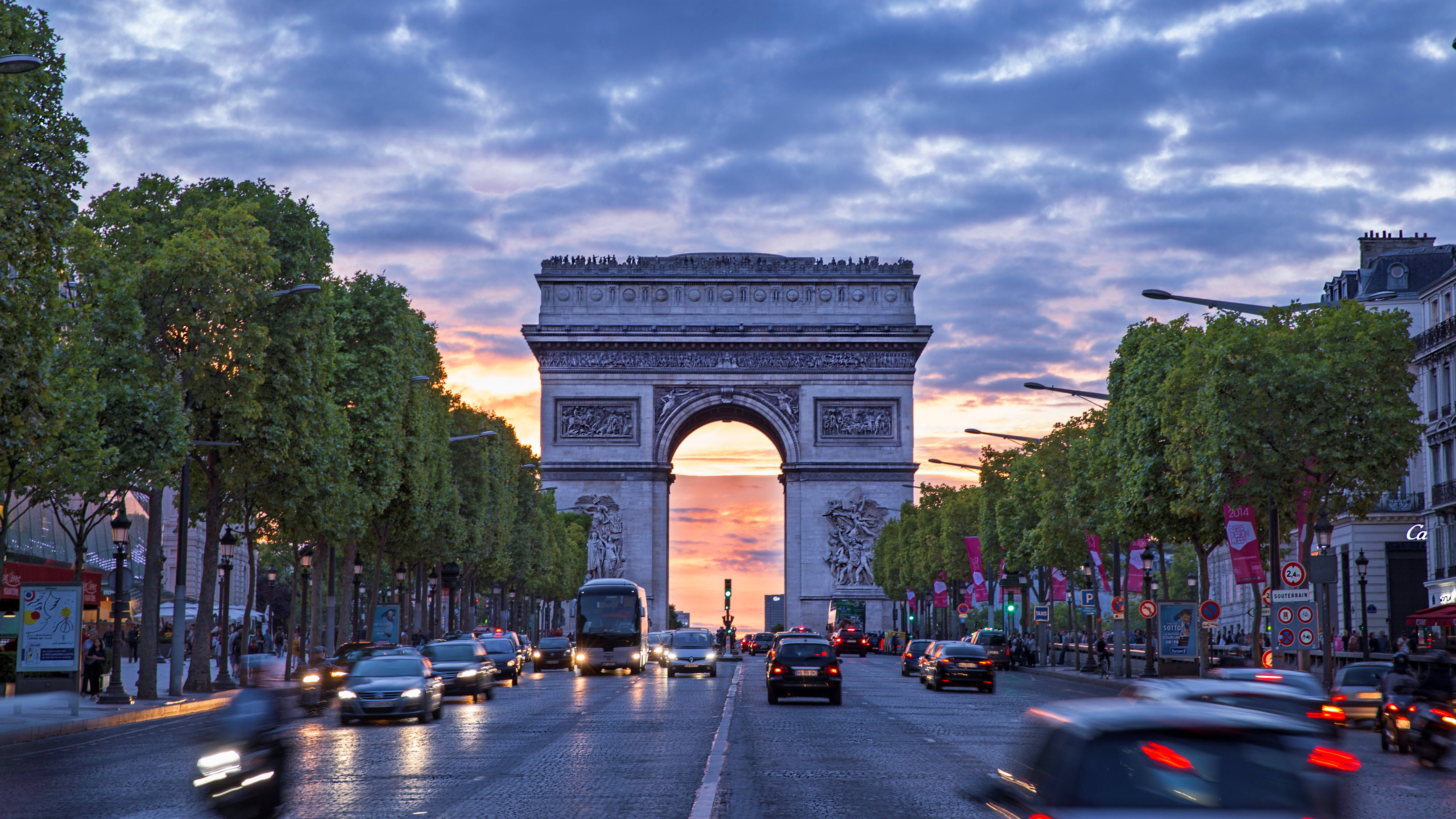 France 桌布 壁紙 — 凱旋門在黃昏時分雄偉地矗立，汽車在充滿活力的暮色天空下模糊駛過。