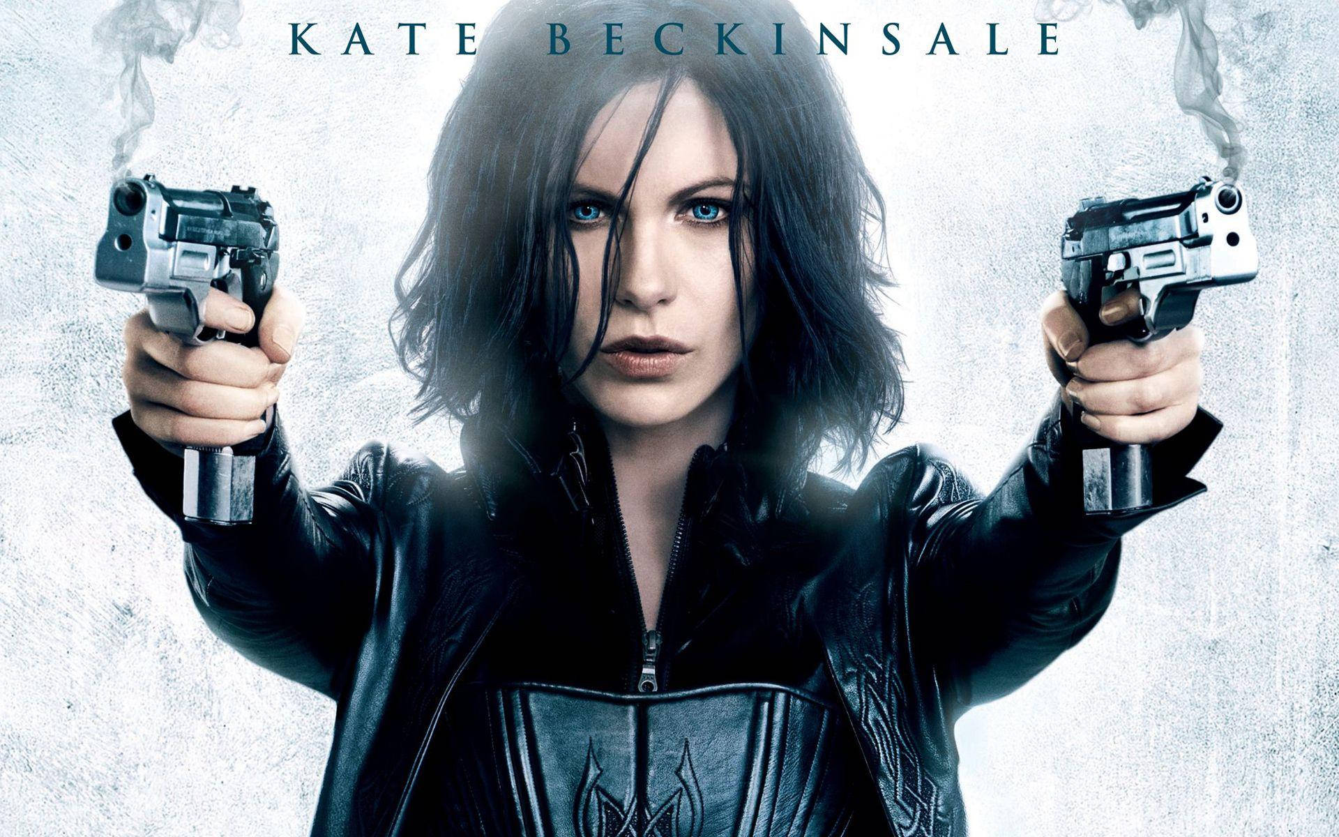 Kate Beckinsale 桌布 壁紙 — 凱特·貝琴薩手持兩把冒煙手槍，在 gritty 電影風格肖像中強烈地向前凝視。