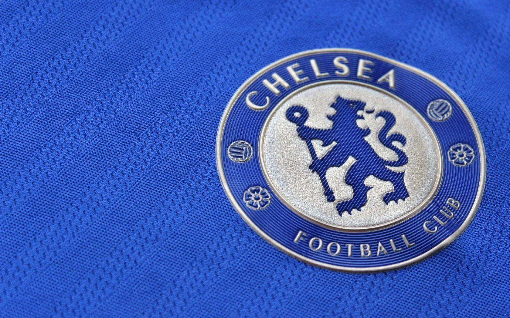 chelsea fc logo 桌布 壁紙 — 切爾西足球俱樂部徽章在皇家藍色紋理球衣布料上的特寫。