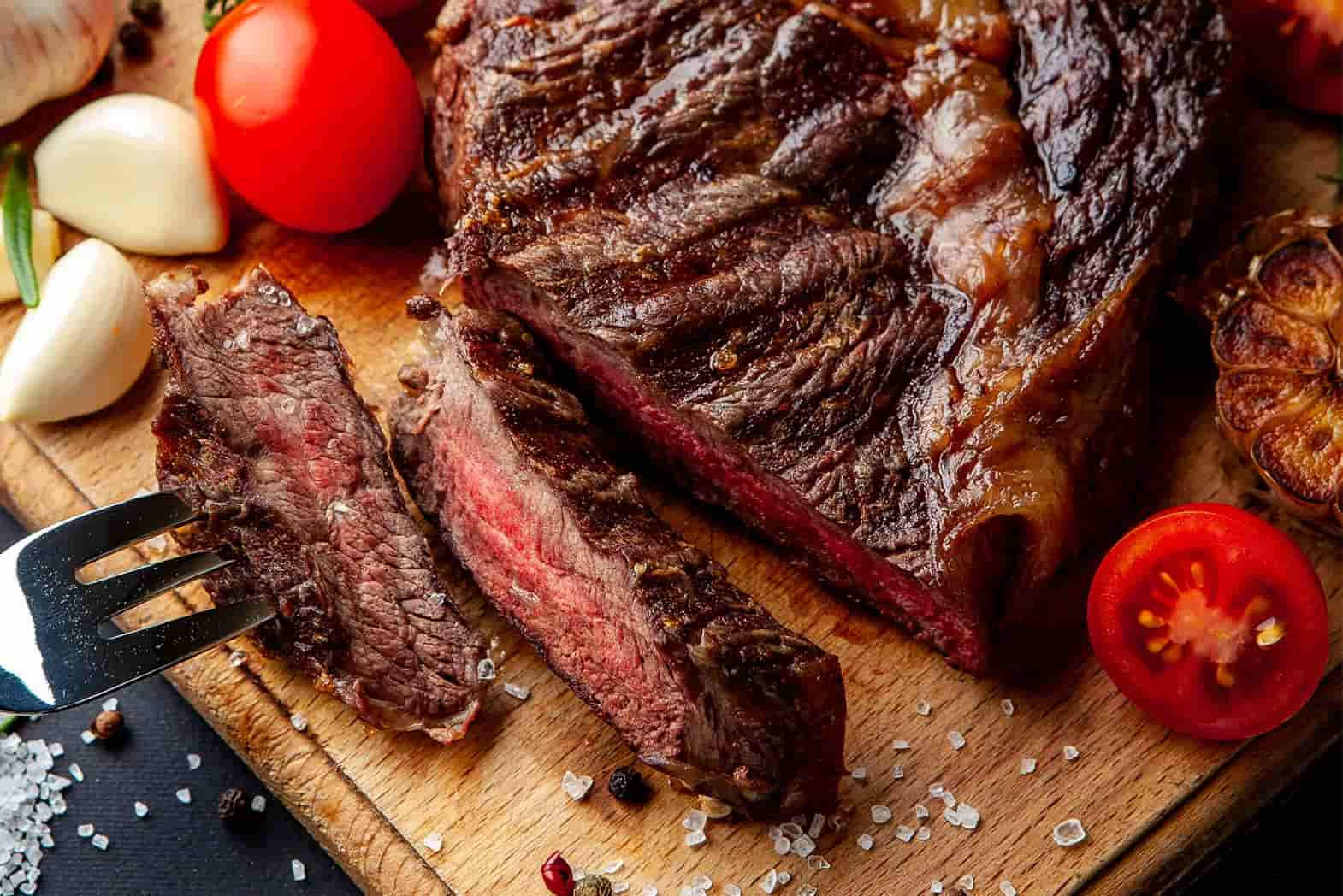 meat 桌布 壁紙 — 切片五成熟牛排搭配蒜香番茄和鹽，放在木板上。