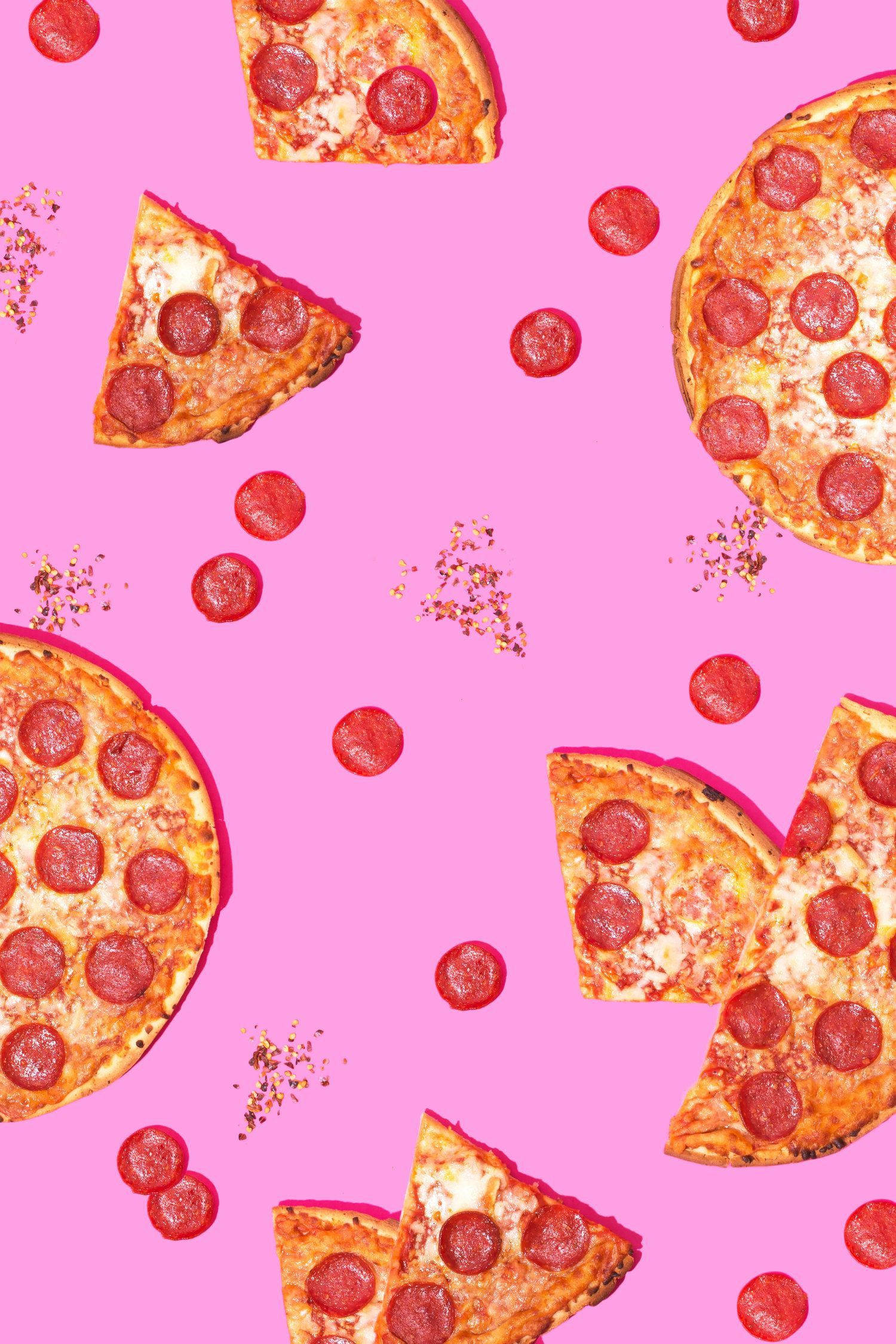 Pizza 桌布 壁紙 — 切片和整個義大利辣香腸披薩漂浮在充滿活力的粉紅色背景上，上面散落著義大利辣香腸和調味料。