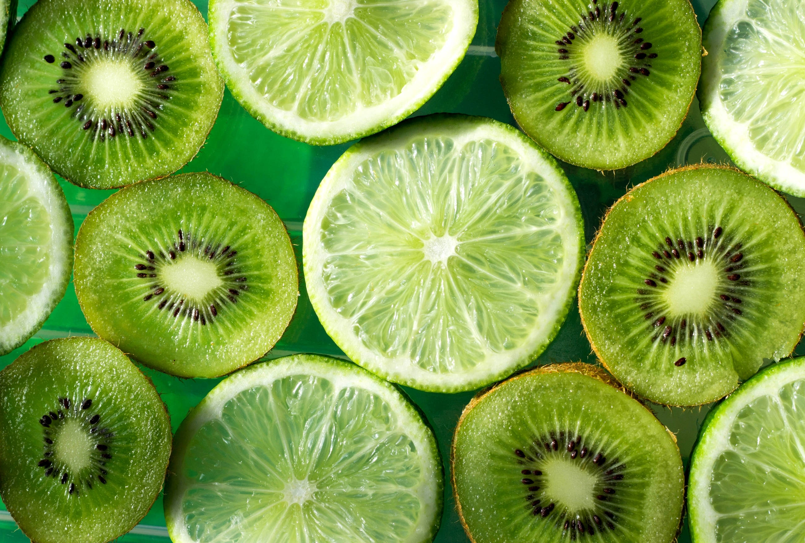 Fruits 桌布 壁紙 — 切片奇異果和萊姆在相配的表面上排列成充滿活力的綠色圖案。