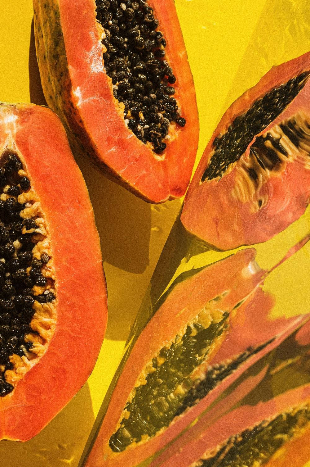 Fruits 桌布 壁紙 — 切片木瓜帶黑色種子漂浮在鮮黃色液體中，營造出多汁的熱帶靜物畫面。