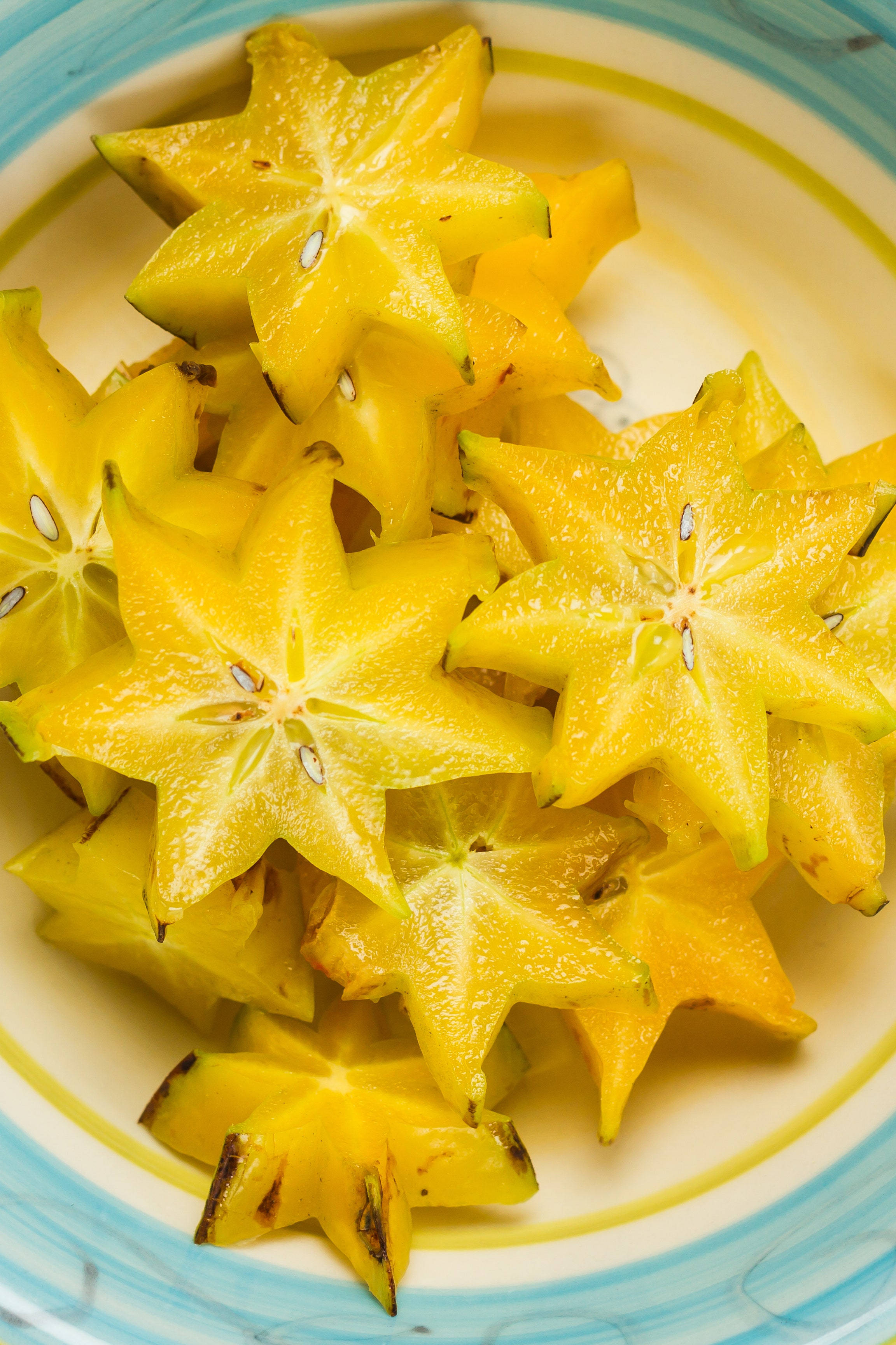 Fruit 桌布 壁紙 — 切片楊桃排列在色彩繽紛的碗中，展示其鮮黃色星形果肉和綠色果皮。