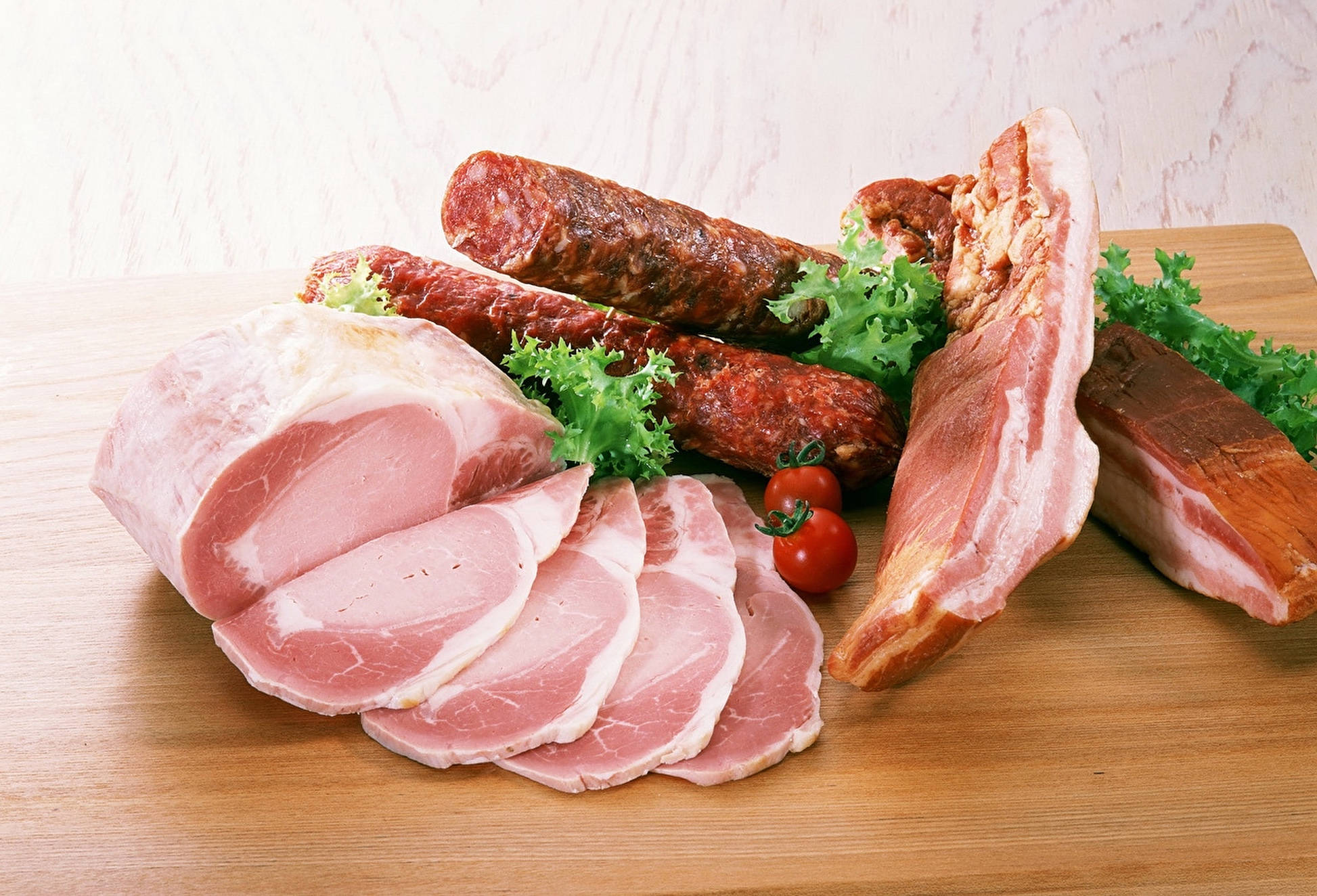 Ham 桌布 壁紙 — 切片火腿、香腸、培根和櫻桃番茄放在木板上，搭配新鮮蔬菜。