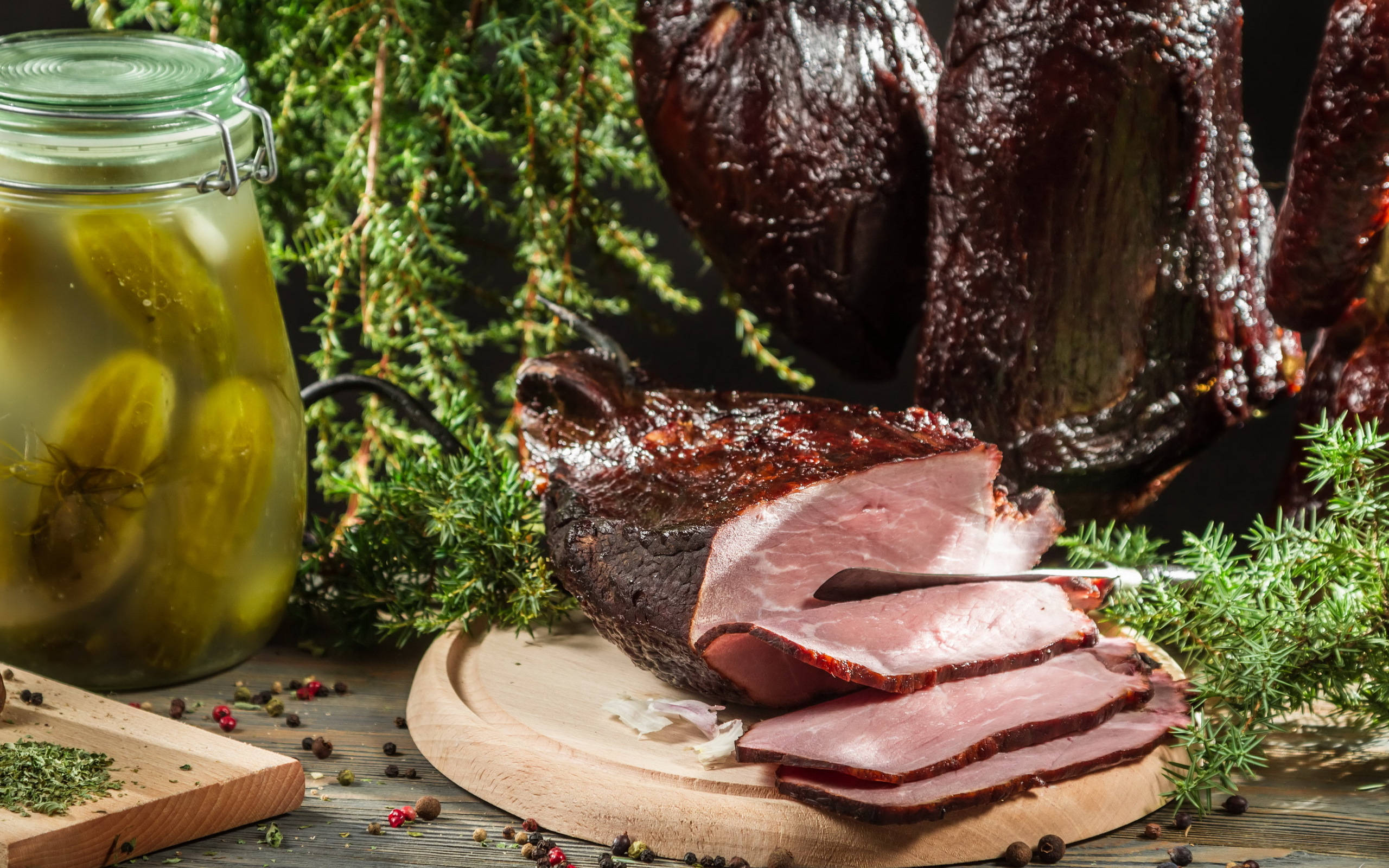 meat 桌布 壁紙 — 切片煙燻火腿和醃黃瓜擺放在木板上，搭配新鮮香草和胡椒粒。