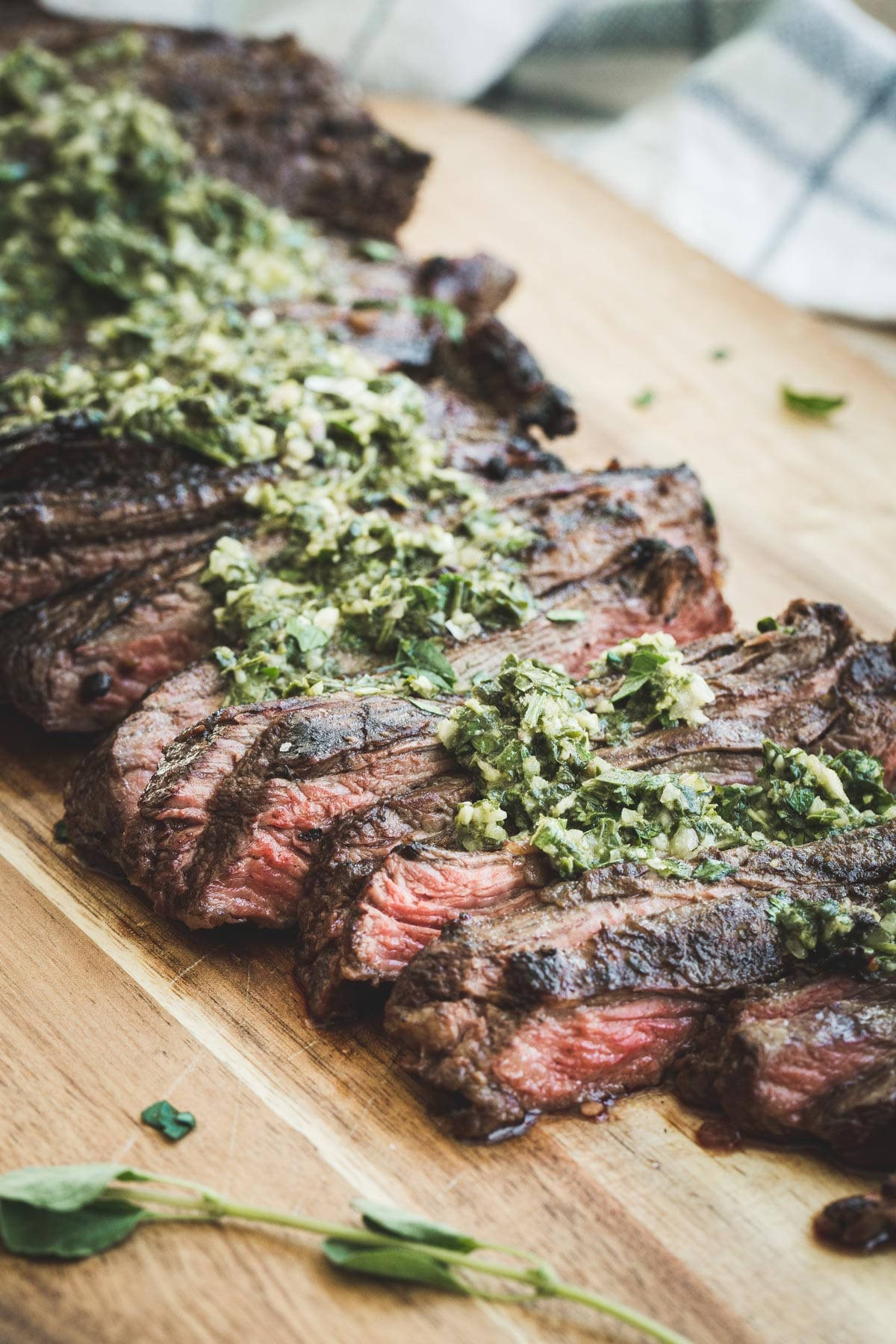 meat 桌布 壁紙 — 切片燒烤牛排佐香草醬，置於木板上，一旁擺放新鮮香草。