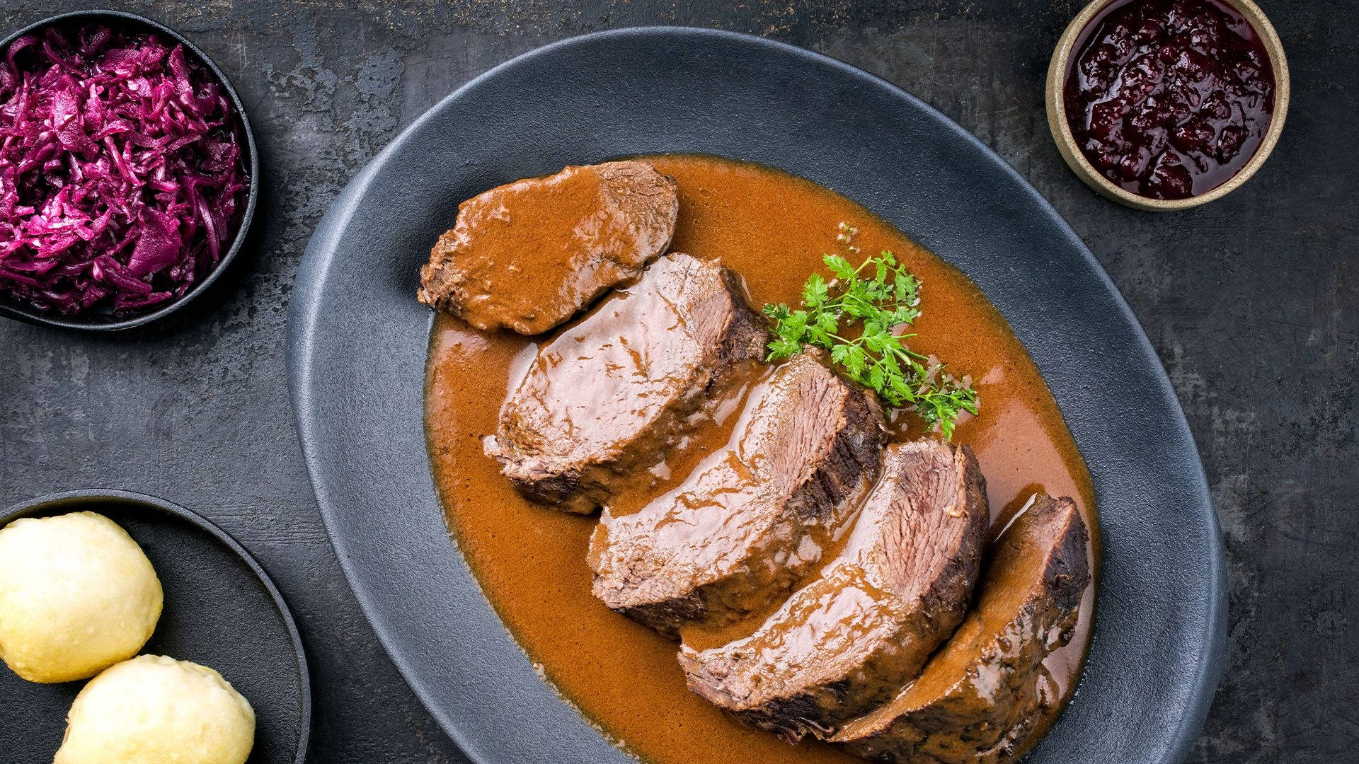 meat 桌布 壁紙 — 切片牛肉配濃郁肉汁，飾以歐芹，佐以紅椰菜和餃子，置於深色紋理表面上。