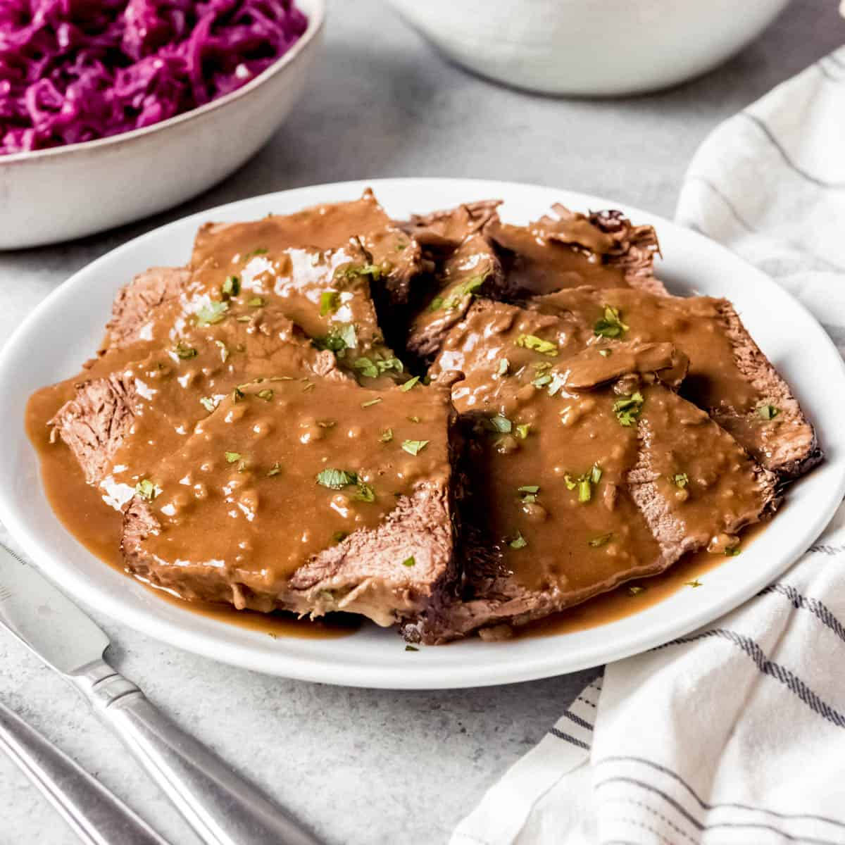 Delicious Food 桌布 壁紙 — 切片牛胸肉浸在濃郁的棕色肉汁和新鮮歐芹中，放在白色盤子上，旁邊有紫高麗菜。