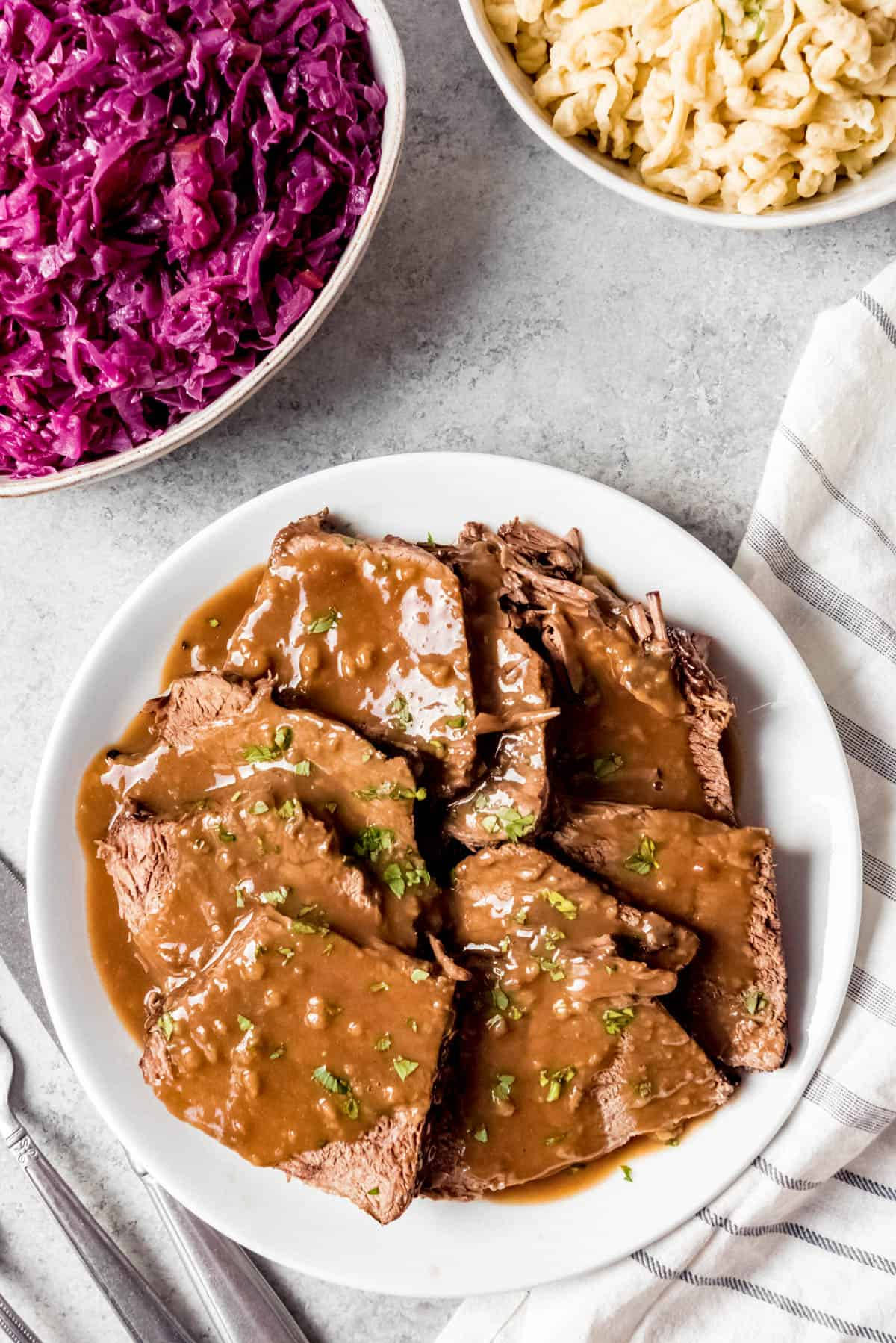 meat 桌布 壁紙 — 切片牛胸肉配上濃郁的棕色肉汁，以歐芹裝飾，搭配鮮豔的紫高麗菜和奶油通心粉沙拉，置於淺灰色表面上。